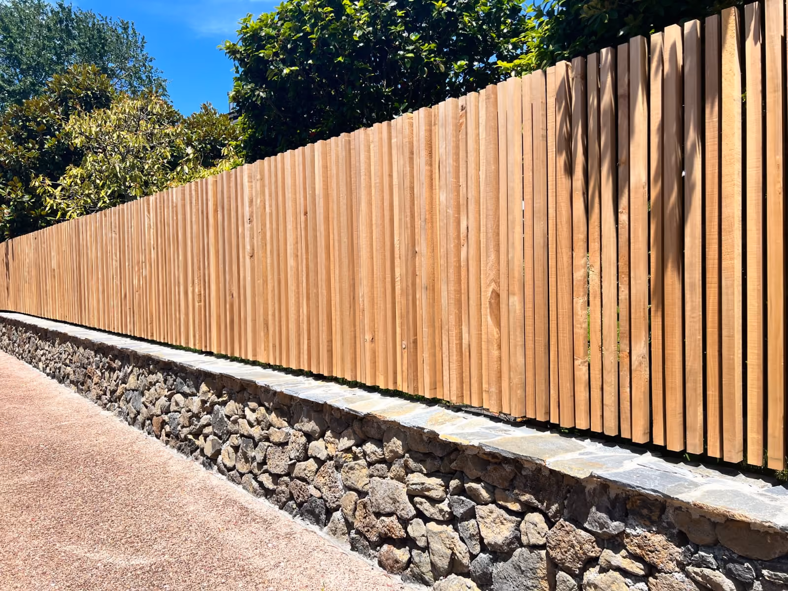 Vertical Macrocarpa timber fence on a stone wall