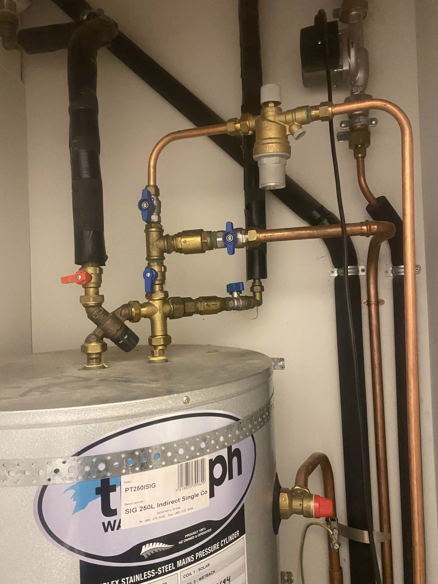 Copper pipework and valves manifolded above a hot water cylinder