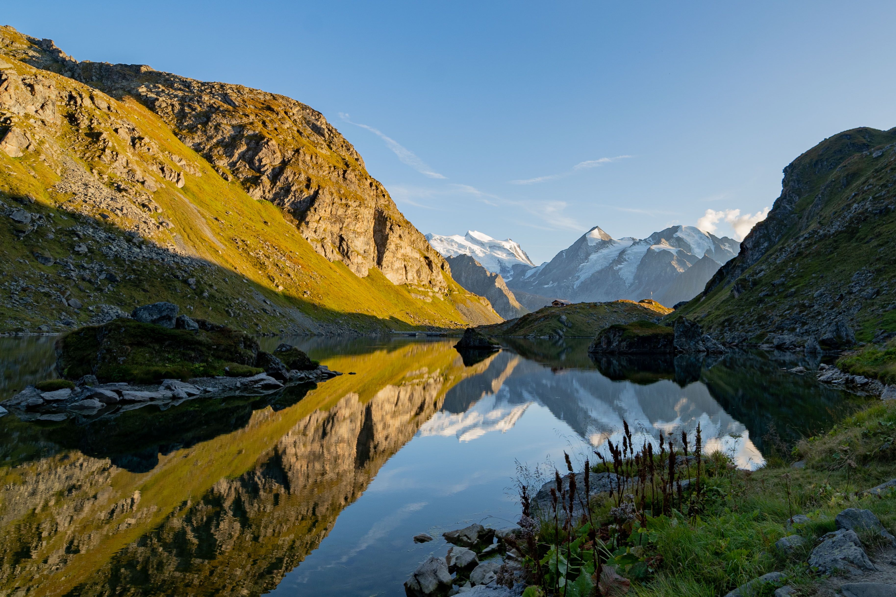 Alpine lake reflecting snow-capped mountains under a clear blue sky