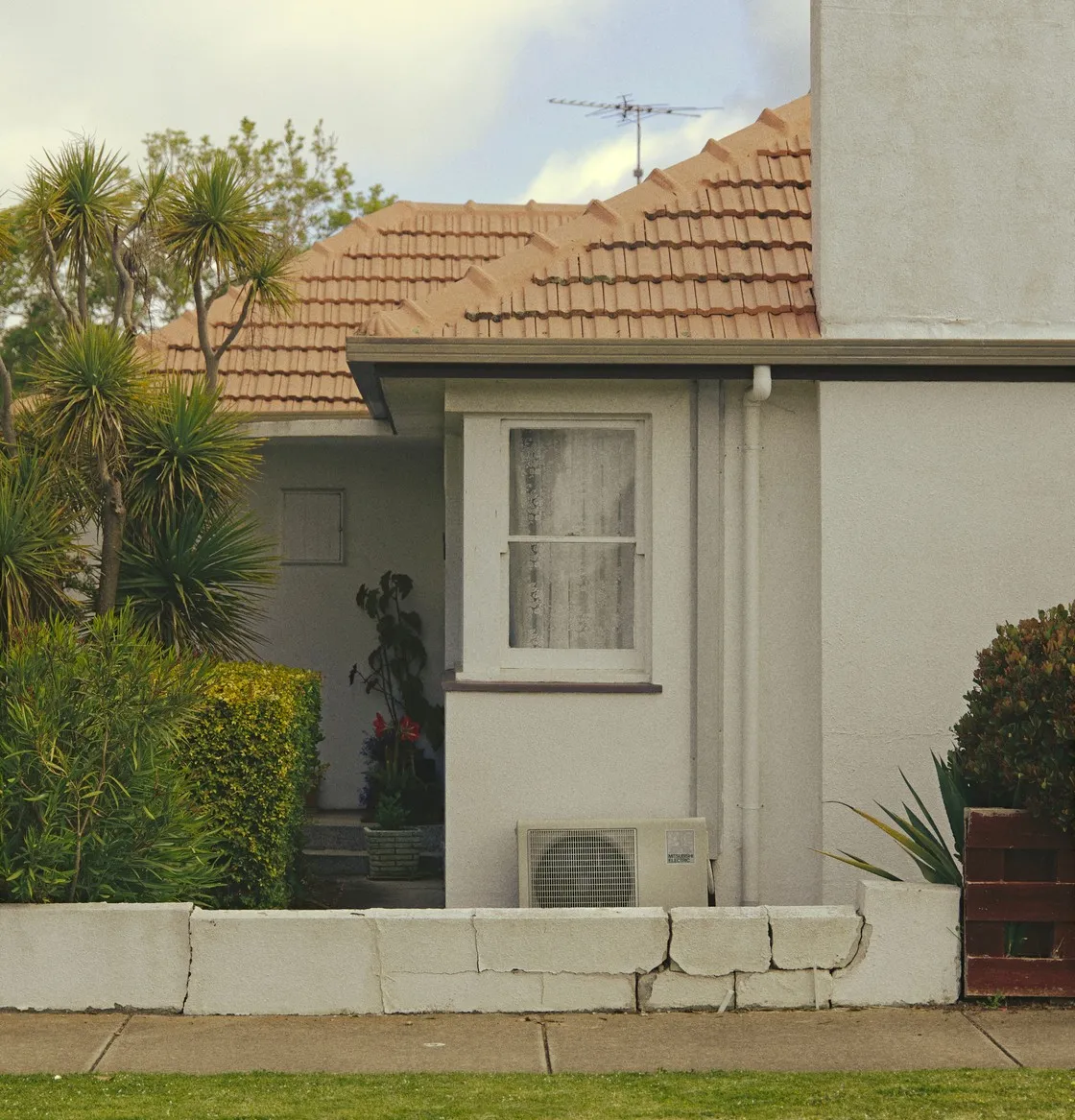 An established home with aged roof tiles, a weathered render wall and a visible crack along the front boundary