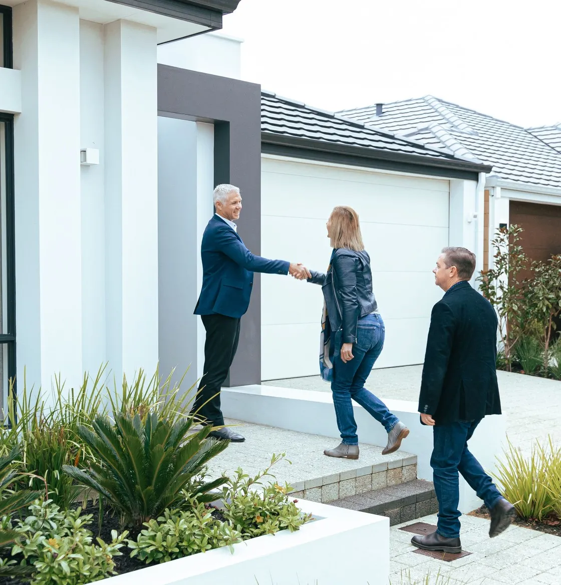 Three people meeting on the front path of a newly completed home
