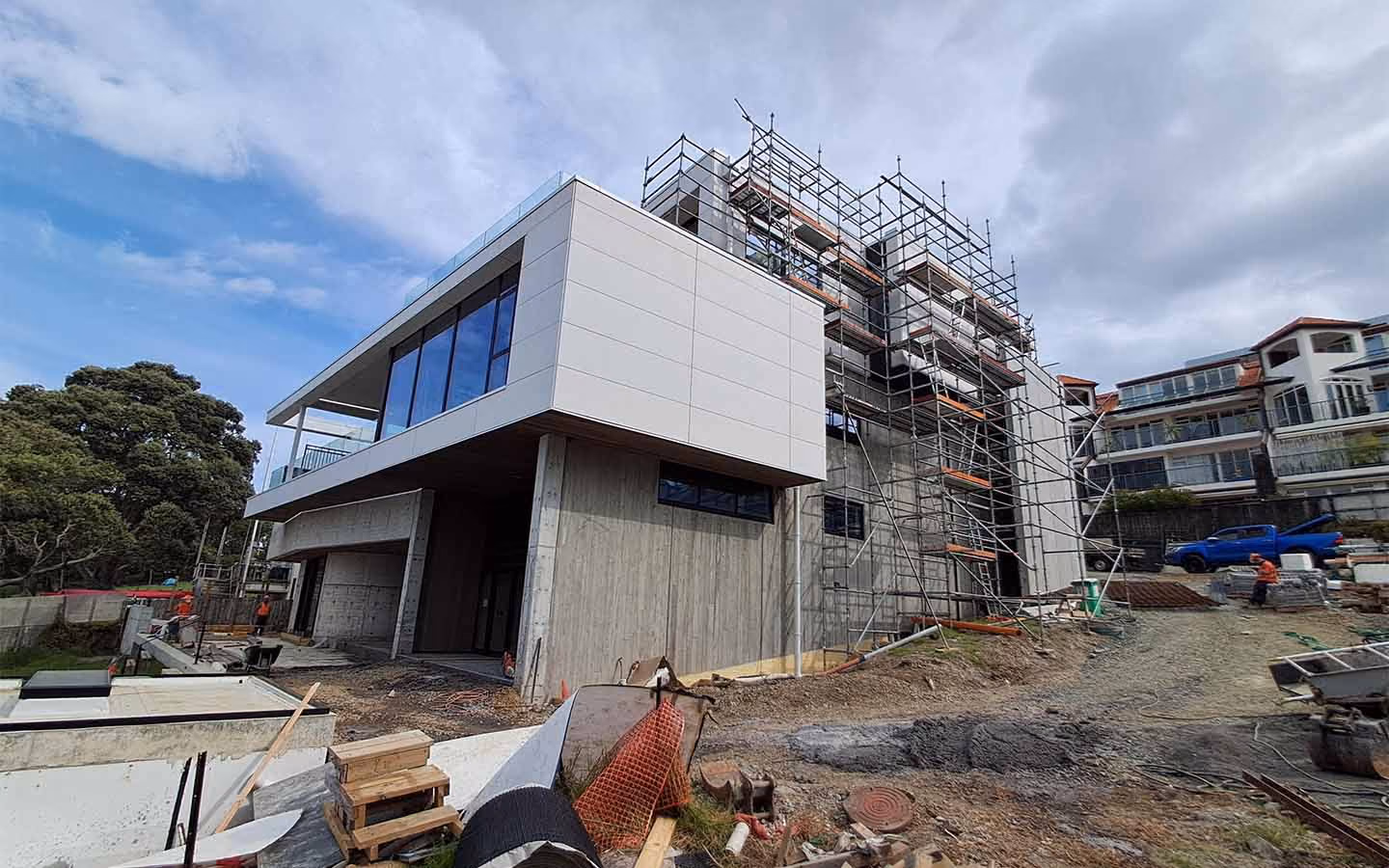 Modern multi-story house under construction with scaffolding and construction materials around.