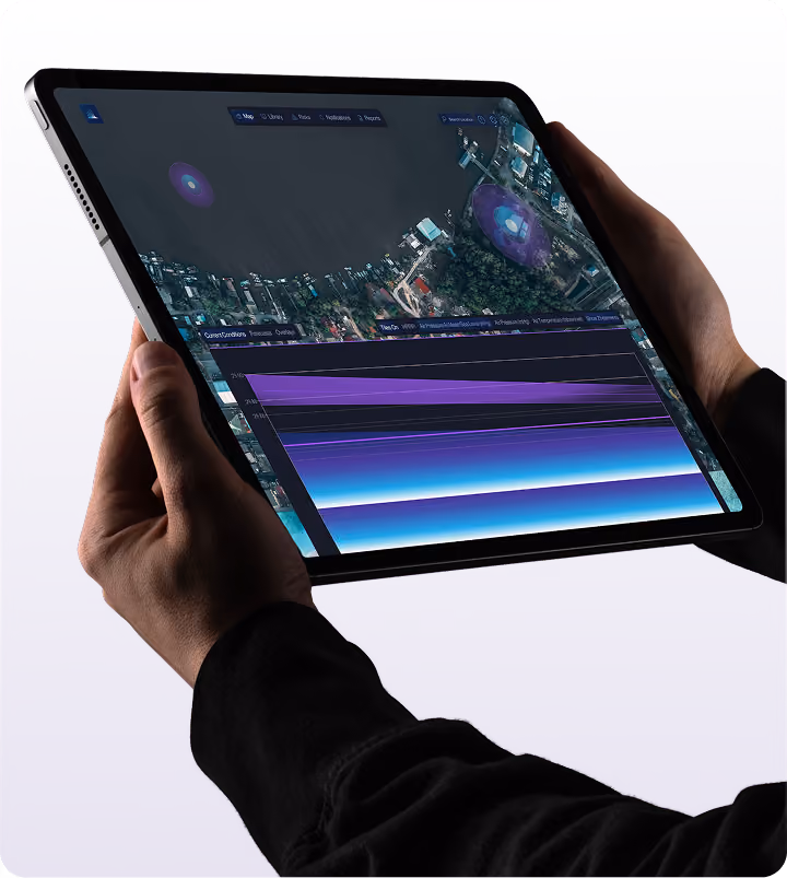 Person holding a tablet displaying a satellite map with data overlays including charts and highlighted areas.