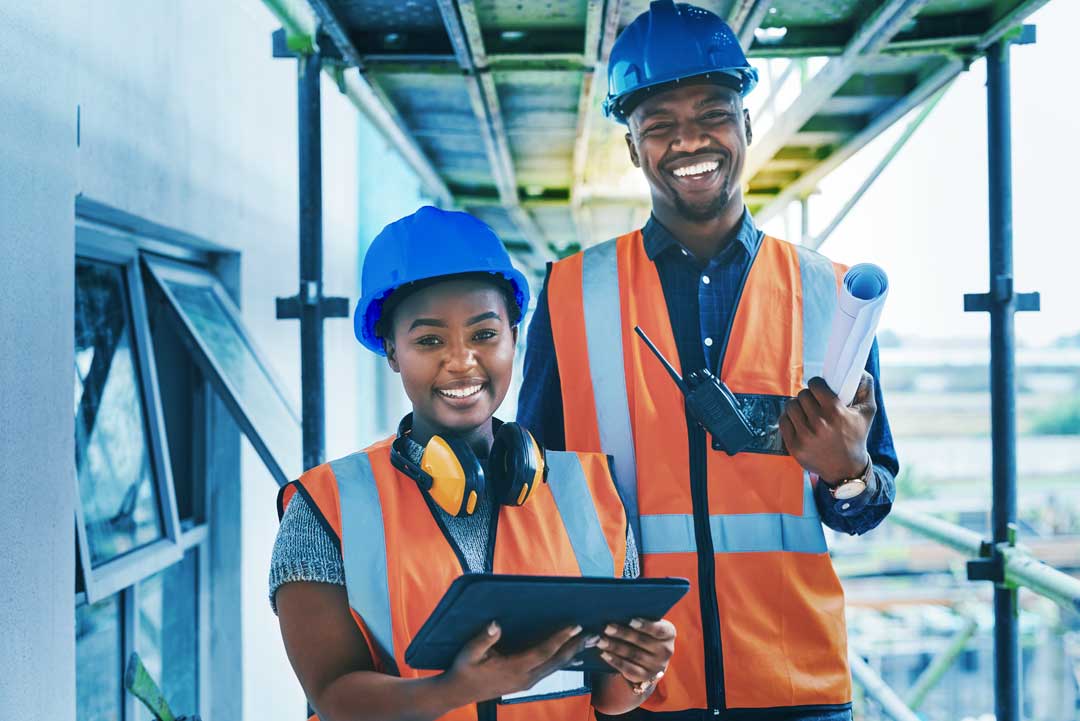 Two smiling Sephaku team members in safety gear on site