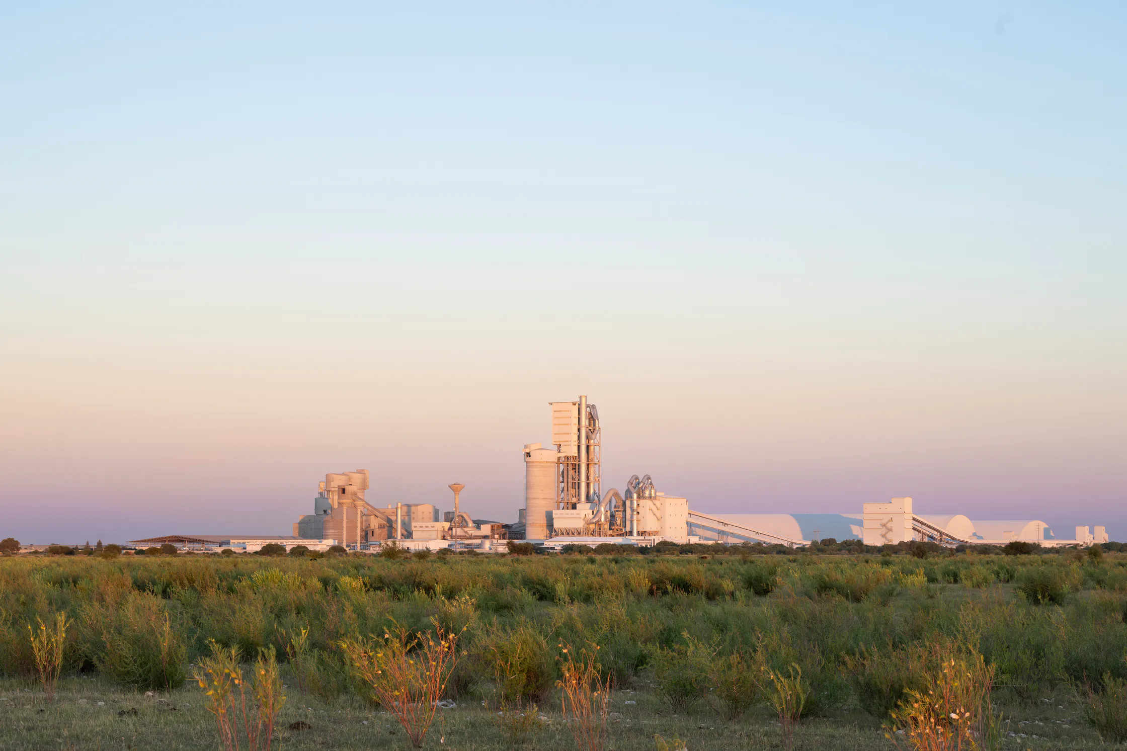 The Aganang clinker plant on the horizon at sunrise, seen across open veld