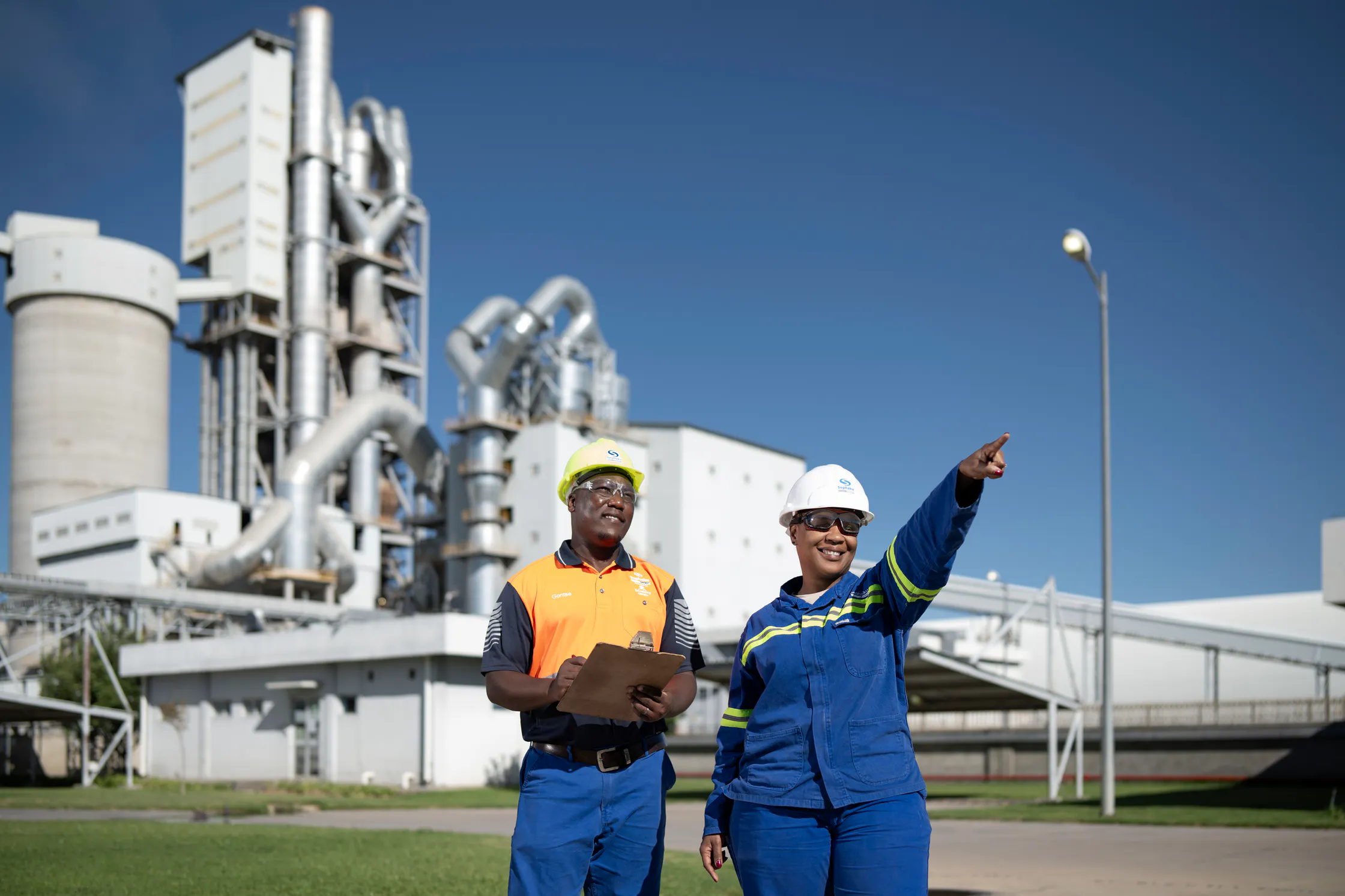 Two Sephaku employees in hard hats reviewing plans outside the Aganang preheater tower