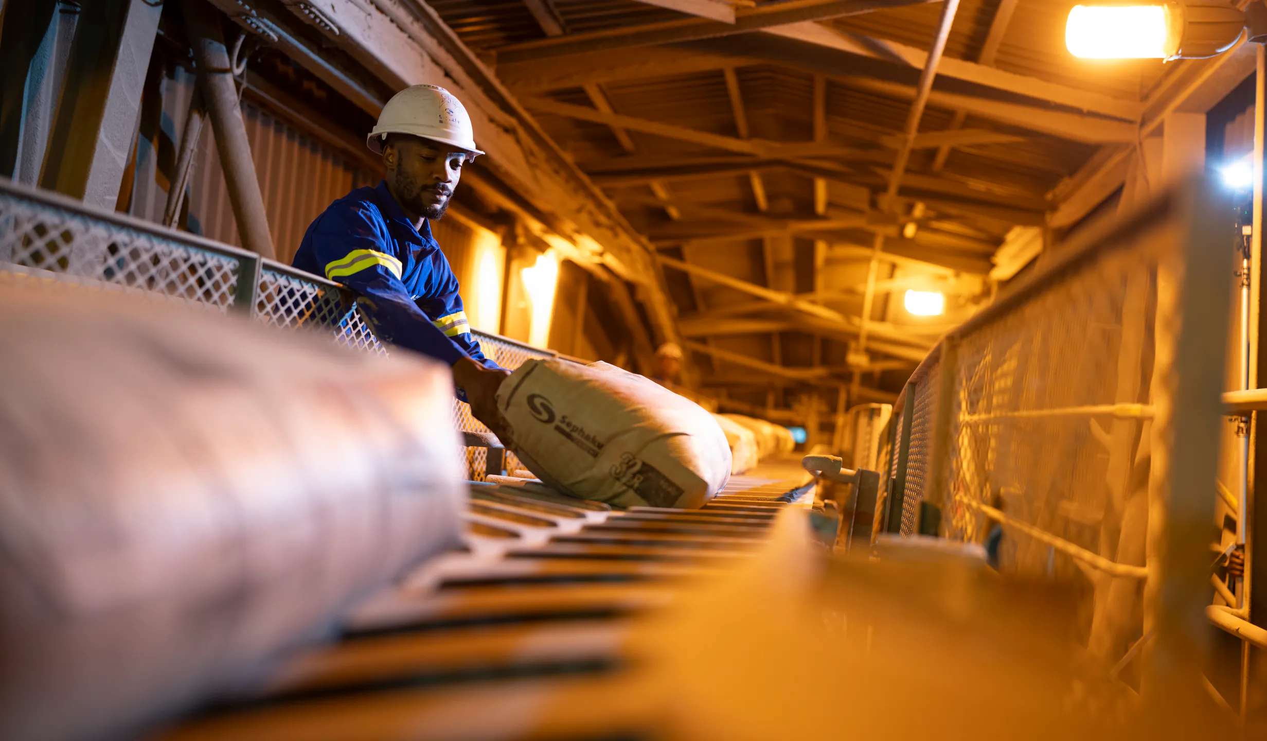Worker guiding cement bags along the packing line at the Delmas plant