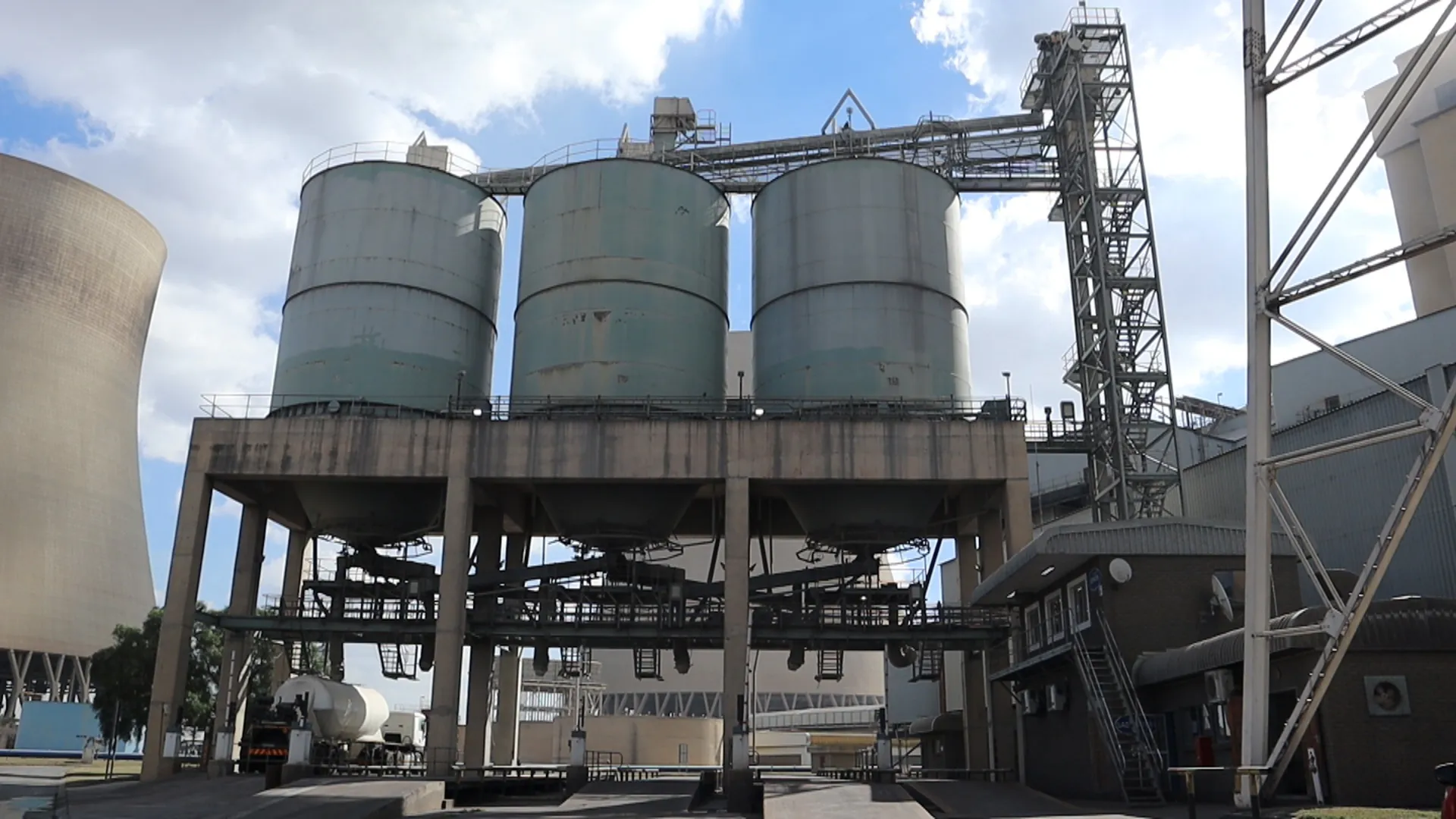 Ash storage silos at the Kendal Ash plant beside a power station cooling tower