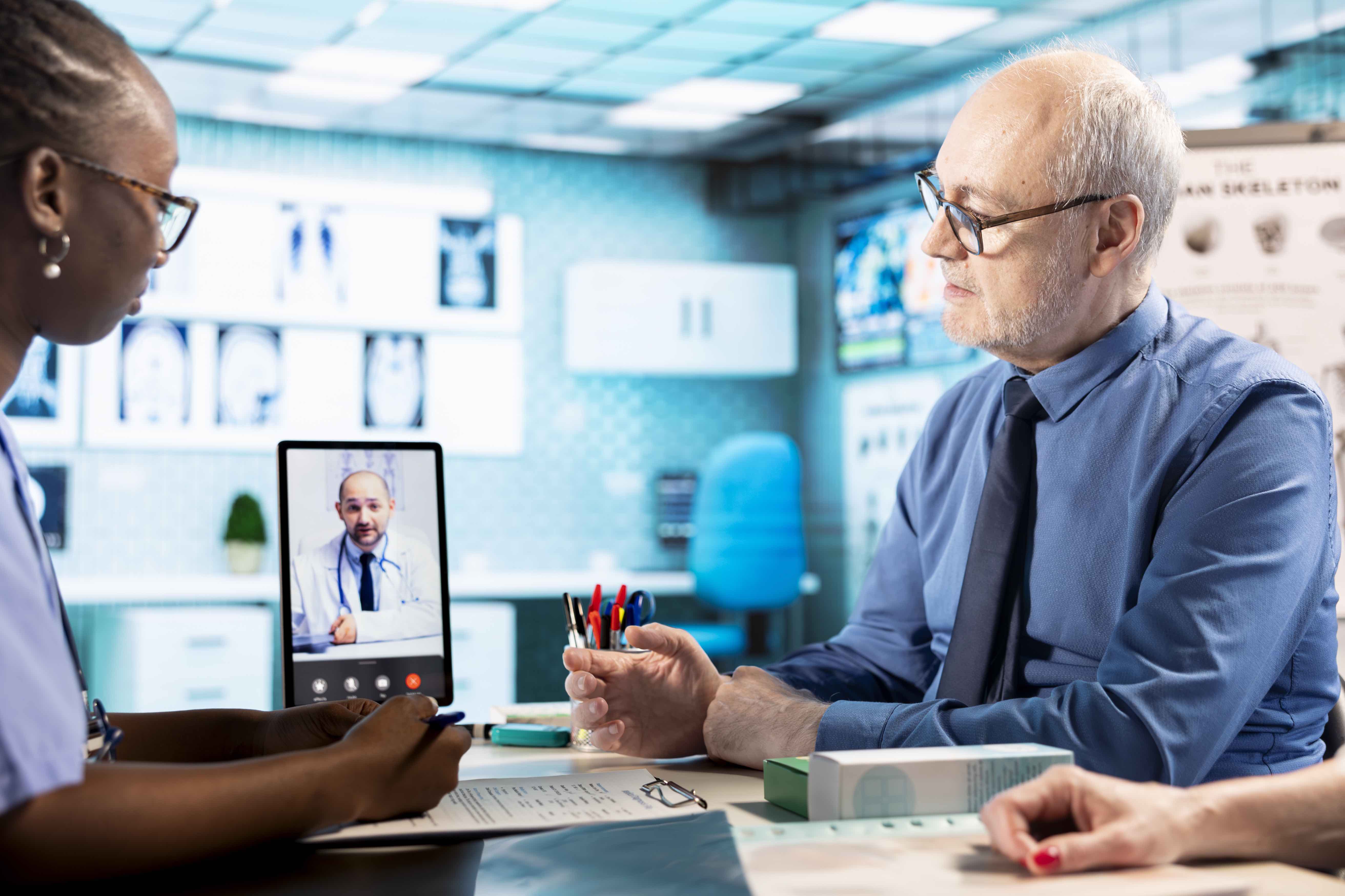Nurse consulting with a patient while on a video call with a physician