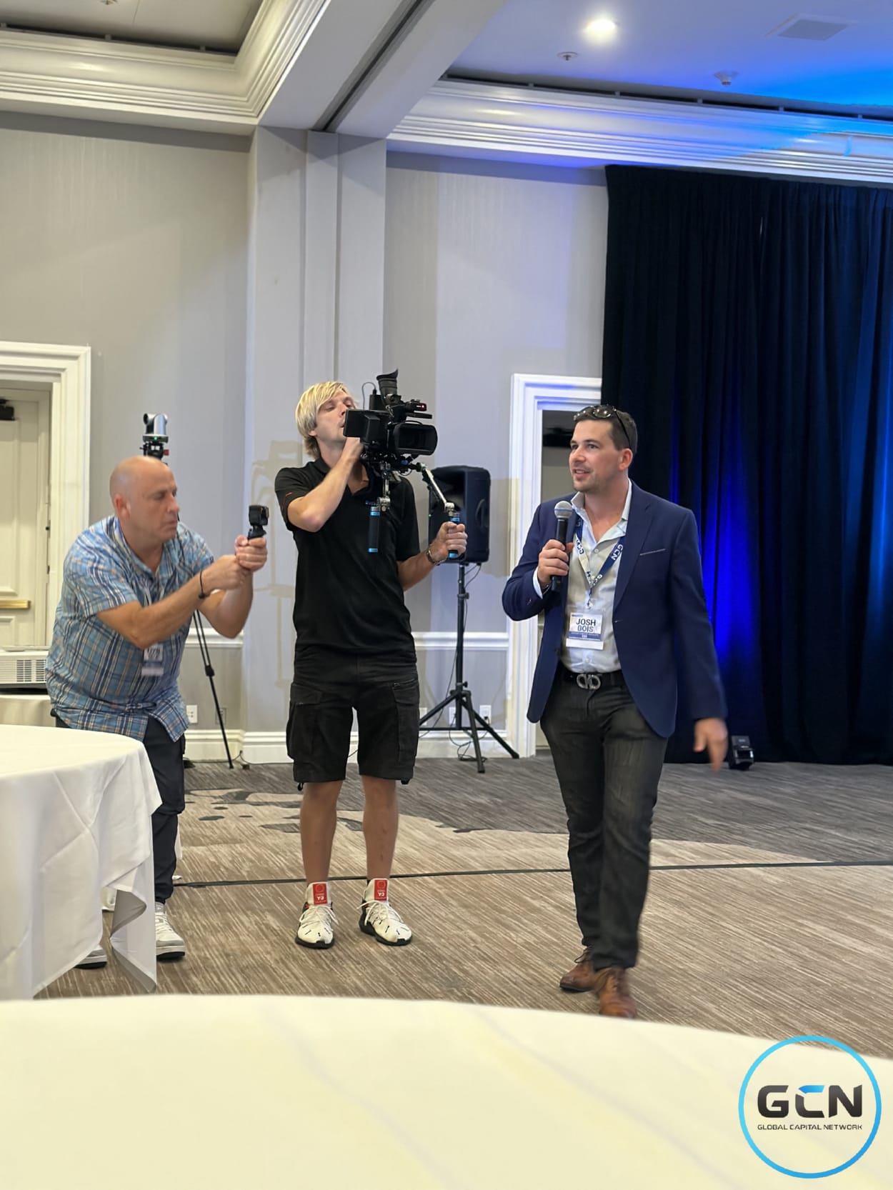 Josh Bois presenting to camera with a film crew at a GCN investor conference