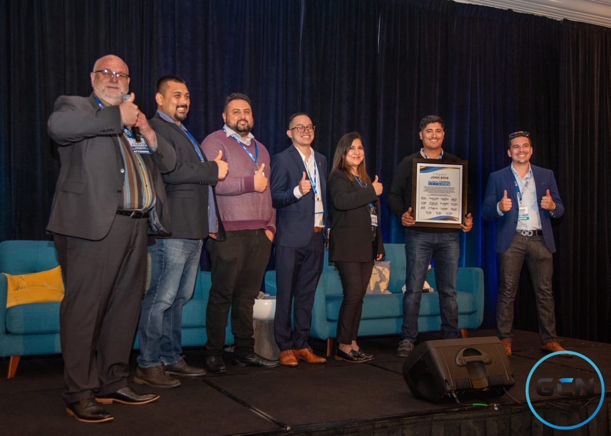 Josh Bois with a group receiving a framed recognition award on stage