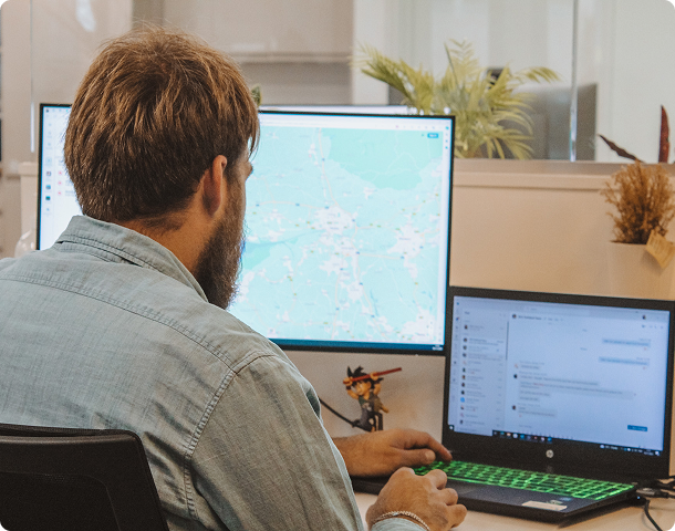 Engineer reviewing site maps and design drawings on two monitors at his desk.