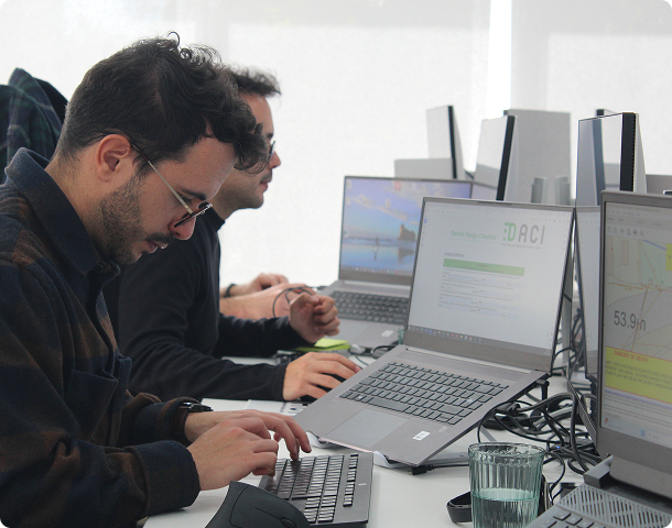 Two engineers working on laptops with design software in an office.