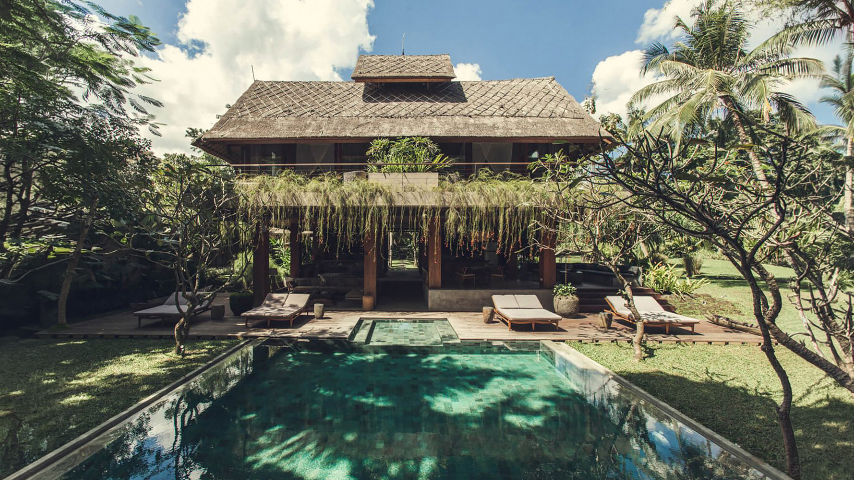 Thatched villa and pool set within the tropical garden