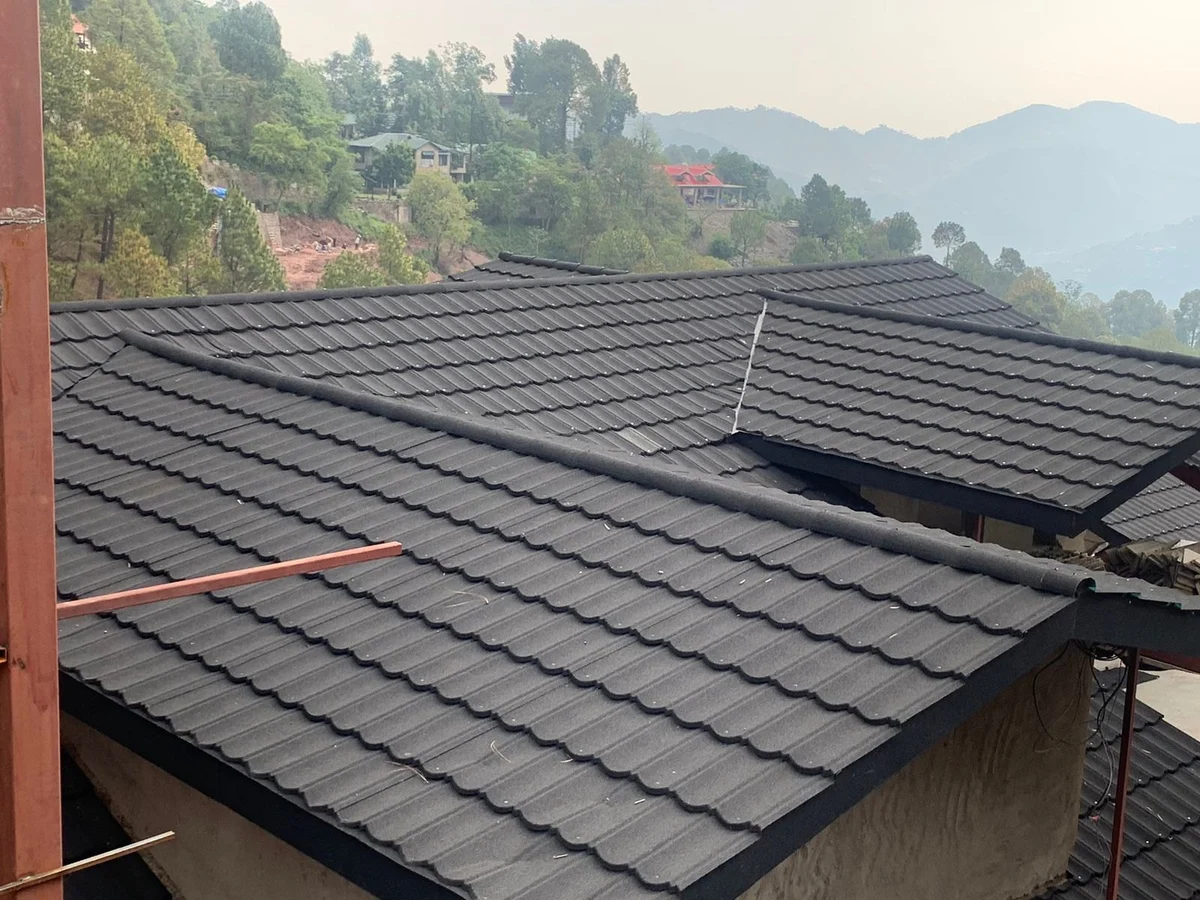 Dark tile-profile stone-coated metal roofing across intersecting pitched roof slopes
