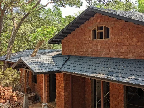 Stone-coated tile-style roof on a brick cottage surrounded by trees