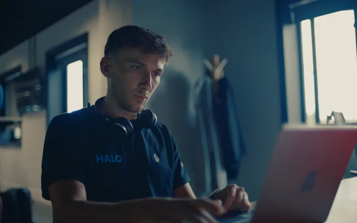 A Halo team member in a branded t-shirt working on a laptop