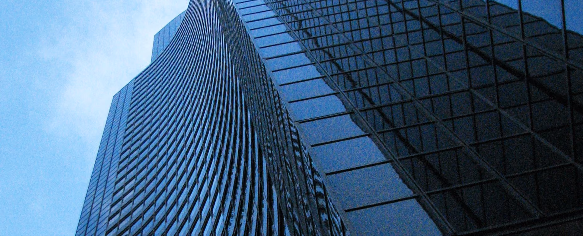 Low-angle view looking up at a modern glass skyscraper.