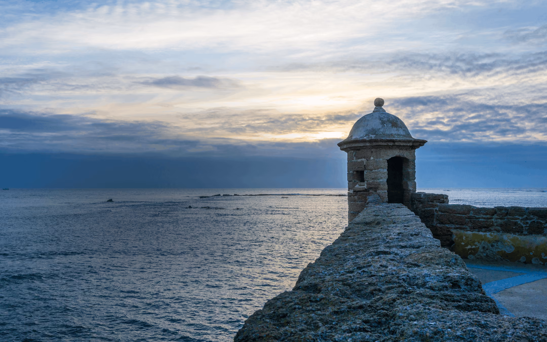 Historic stone sentry box on a sea fortress wall at sunset.