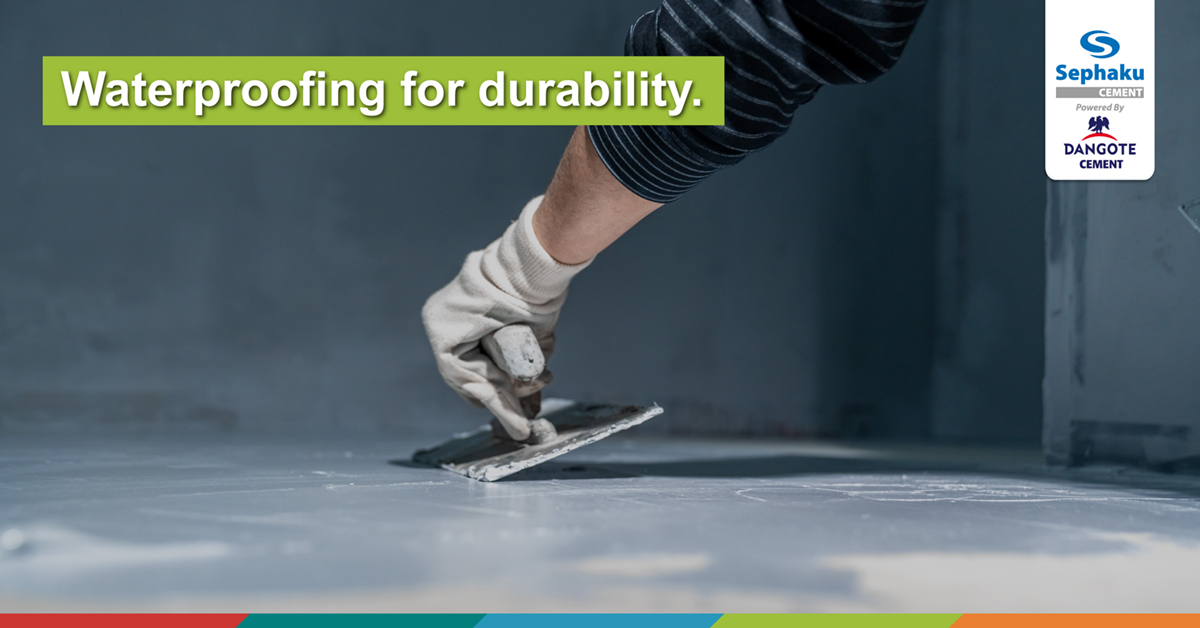 Worker applying a waterproofing membrane to a concrete floor with a trowel, highlighting the importance of waterproofing for durability in construction with Sephaku Cement.