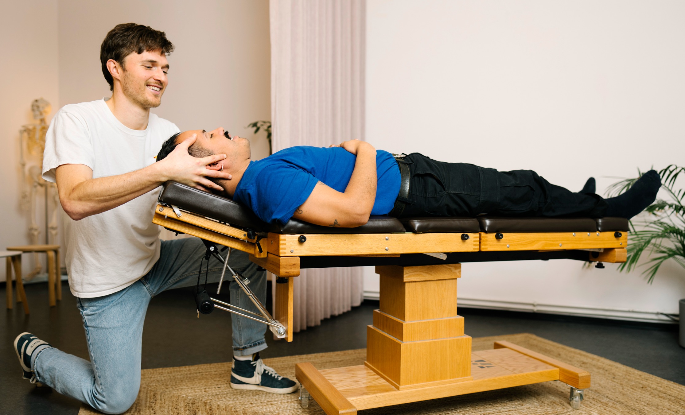 Chiropraktiker Paul justiert die Halswirbelsäule eines liegenden Patienten.
