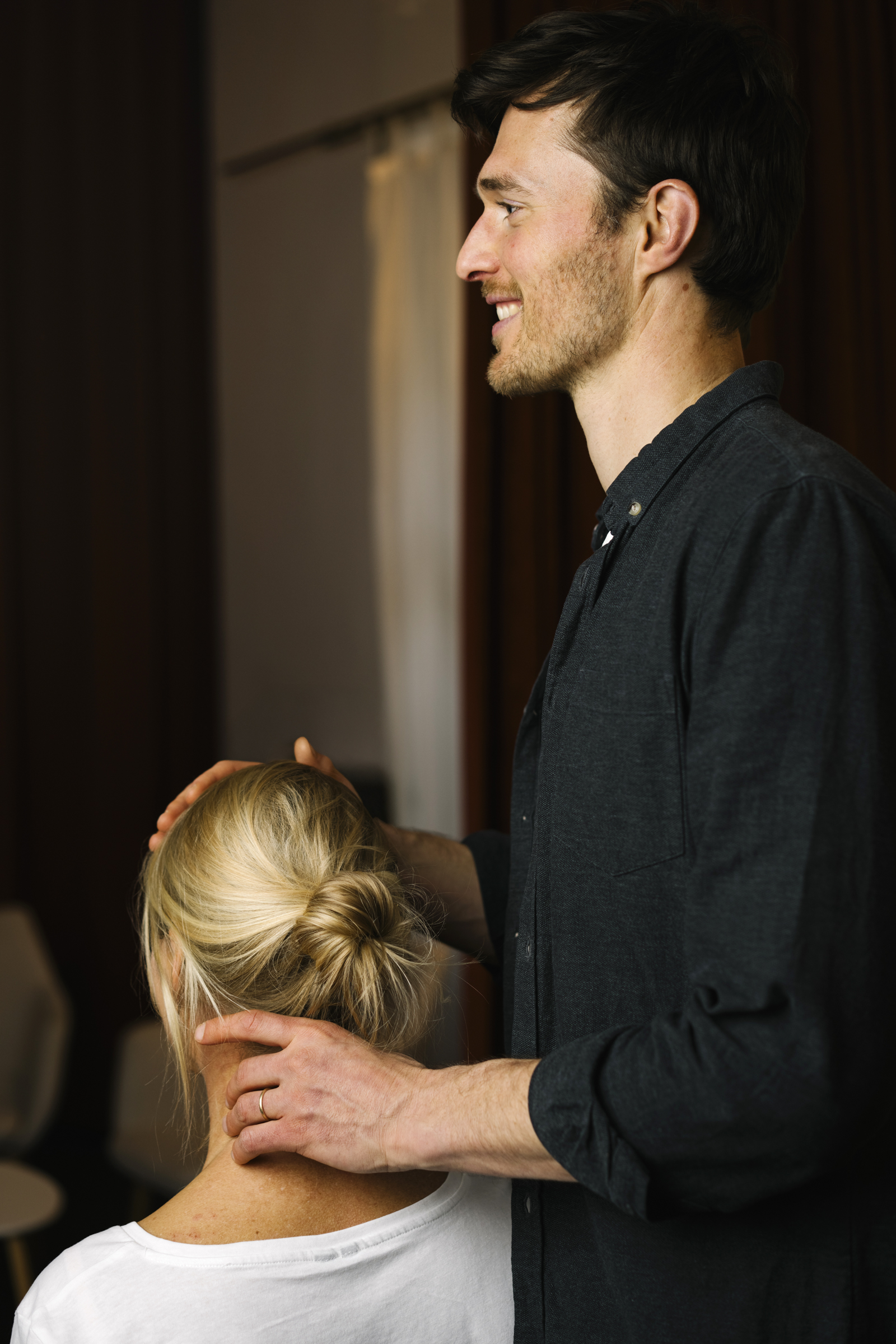 Chiropraktiker Paul tastet die Halswirbelsäule einer Patientin ab.