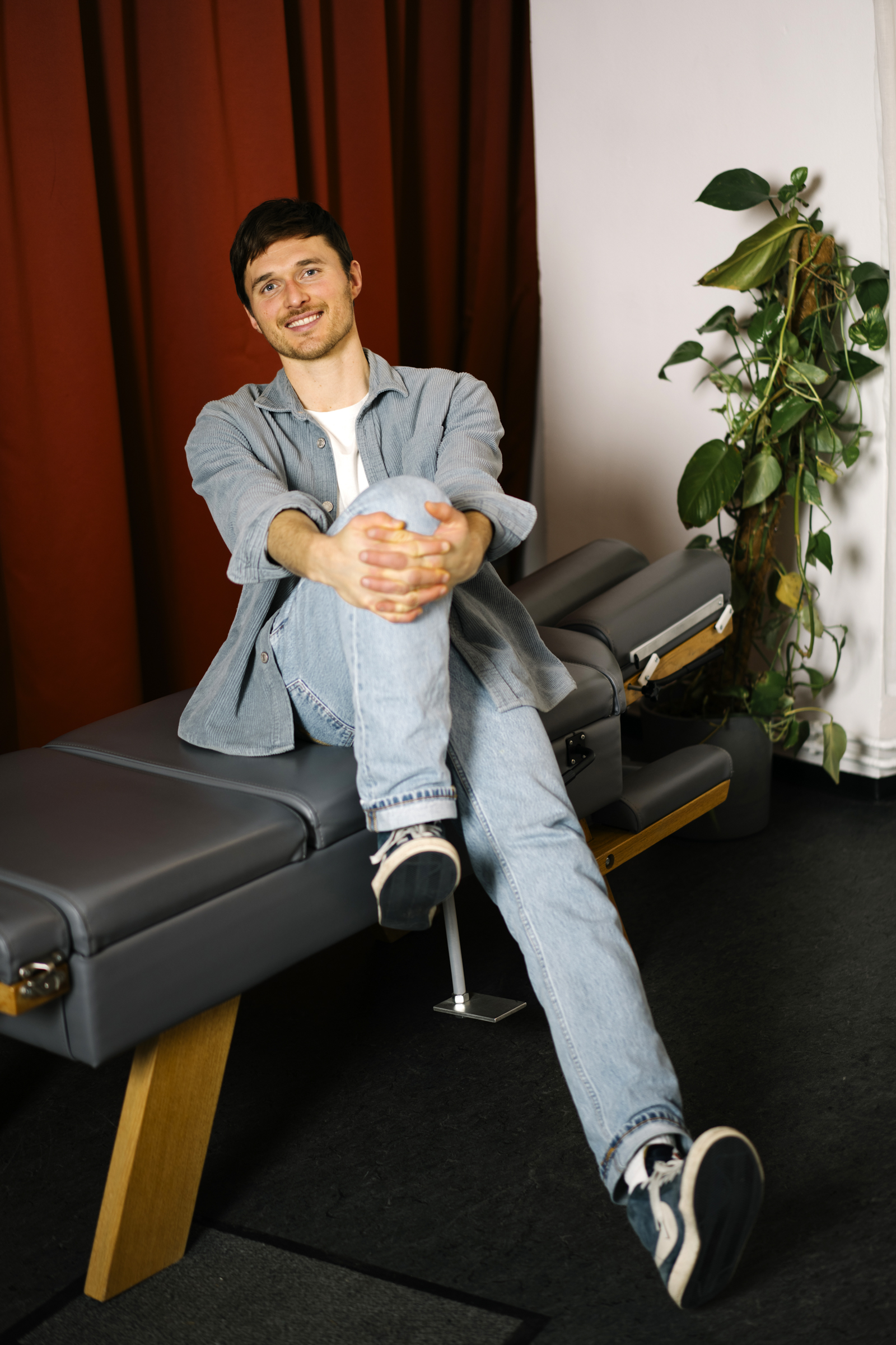 Chiropraktiker Paul Brockdorff sitzt auf einer Chiropraktik-Liege in seiner Praxis.