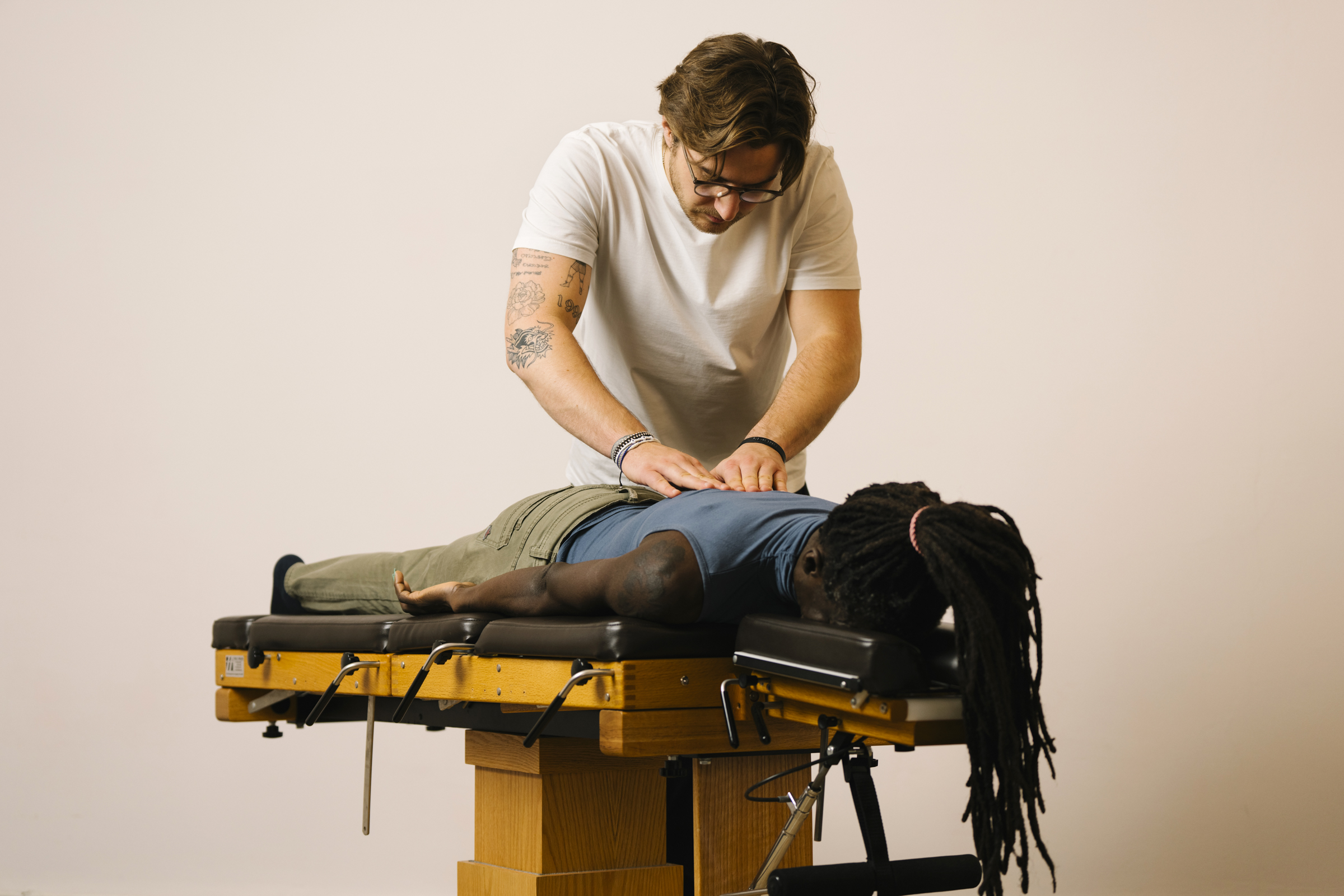 Chiropraktiker Max tastet die Wirbelsäule einer Patientin ab.