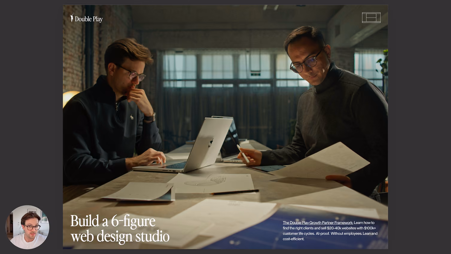 Two men working at a table with laptops and papers in a dimly lit modern office space.