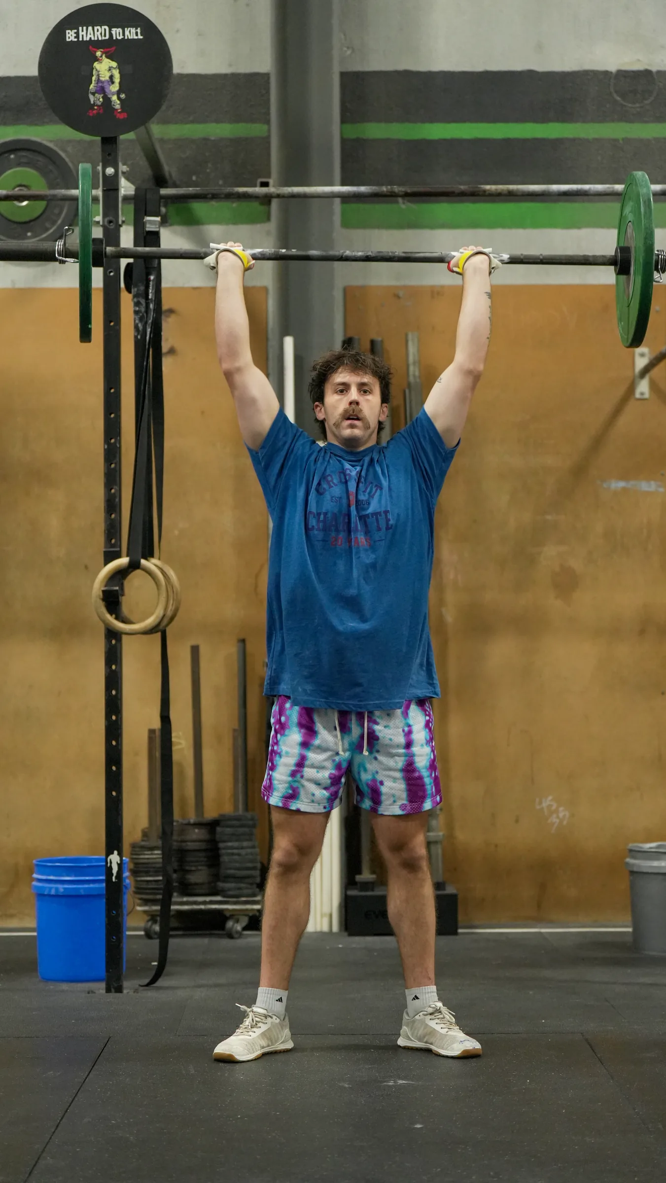 Bryson Delmonte holding a barbell locked out overhead in the gym.