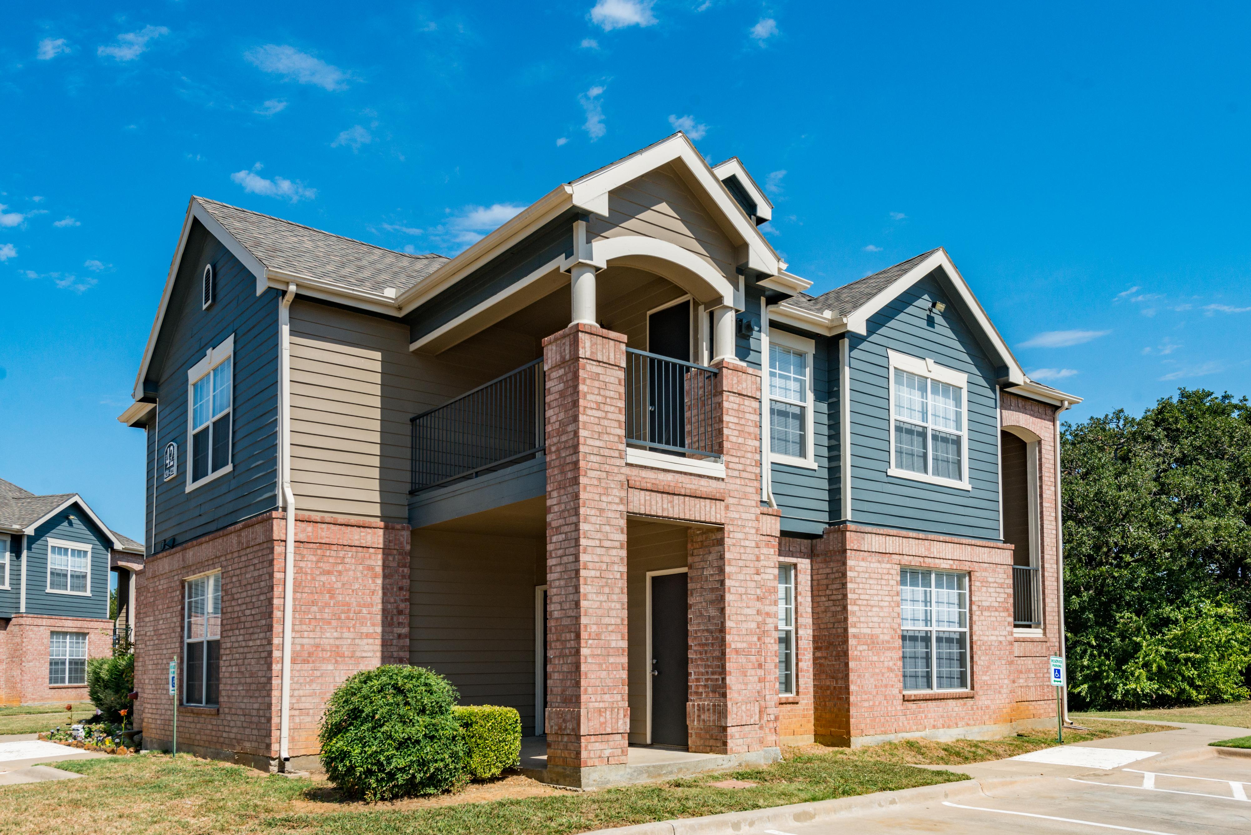 Exterior of apartment building with first-floor patio and second-floor fenced balcony