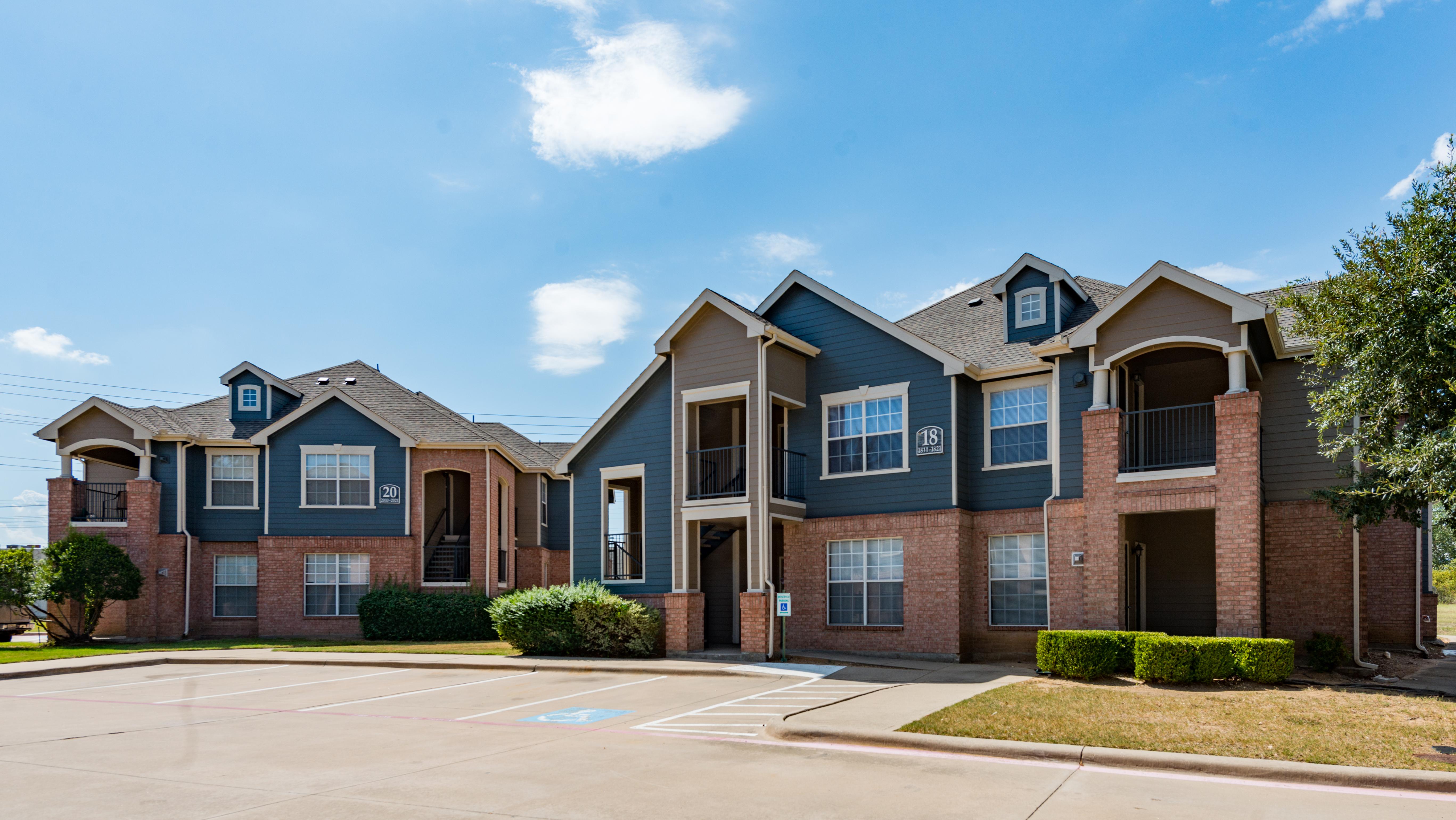 Exterior of apartment building with surrounding landscaping and parking area