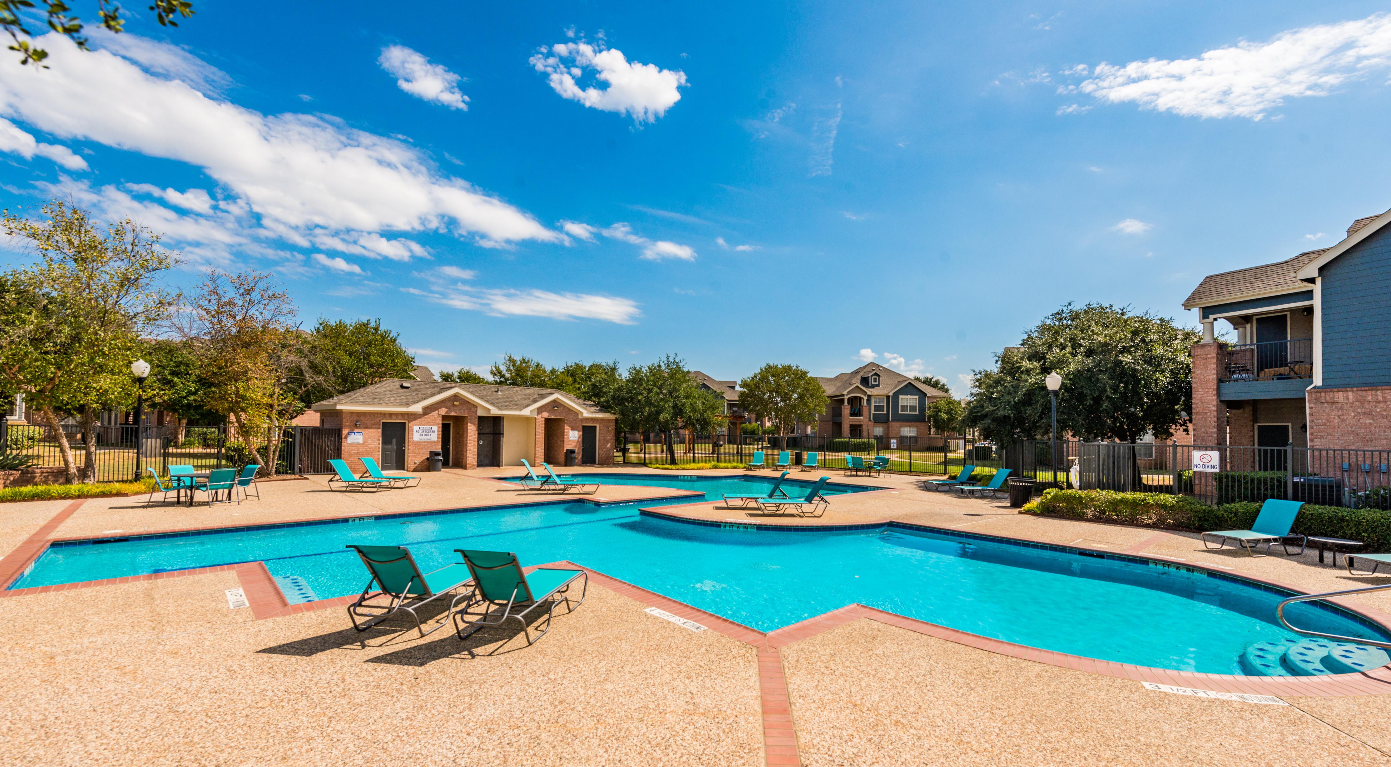 Wide view of swimming pool with outdoor showers in the background