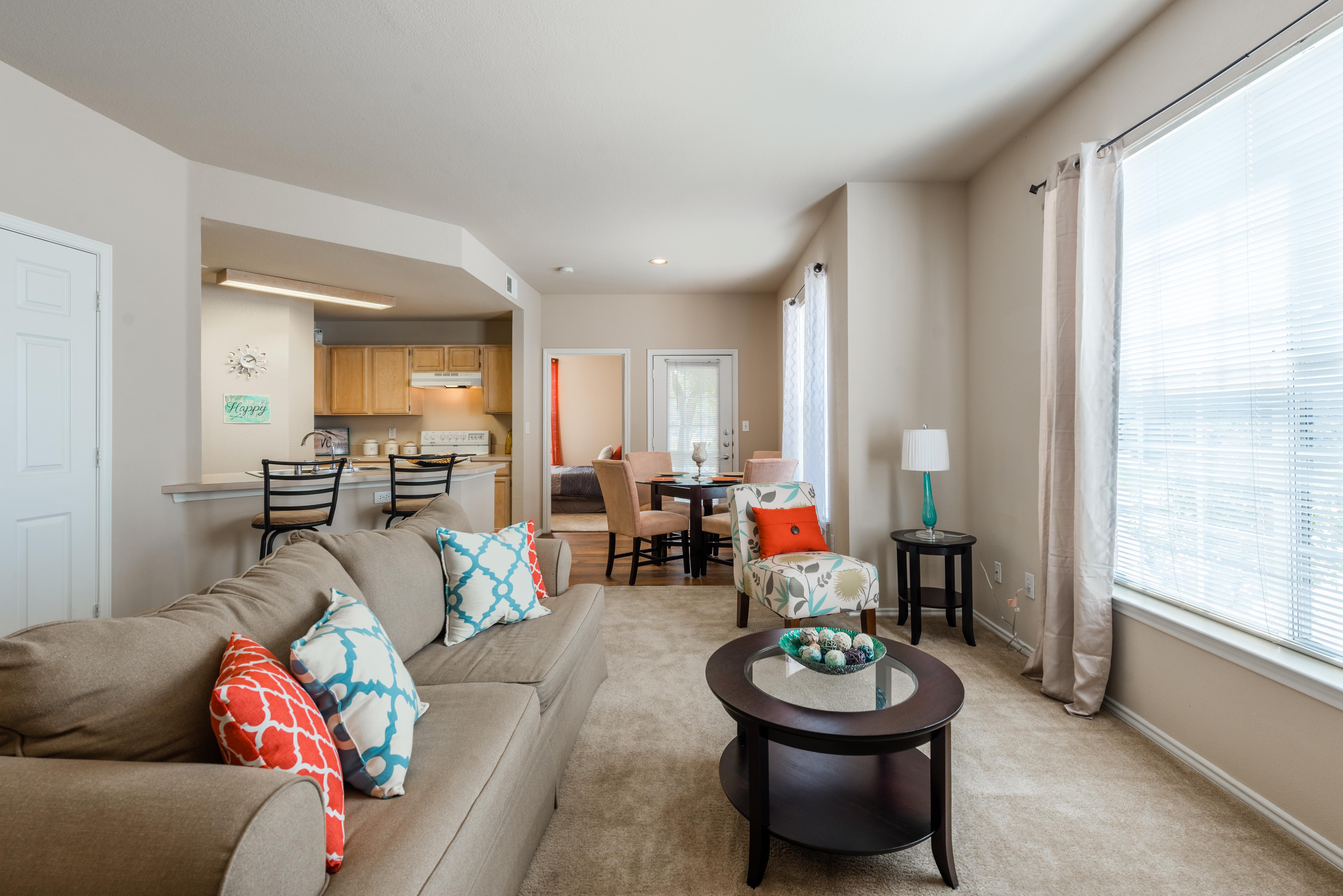 Furnished, carpeted living room with view of kitchen and dining area