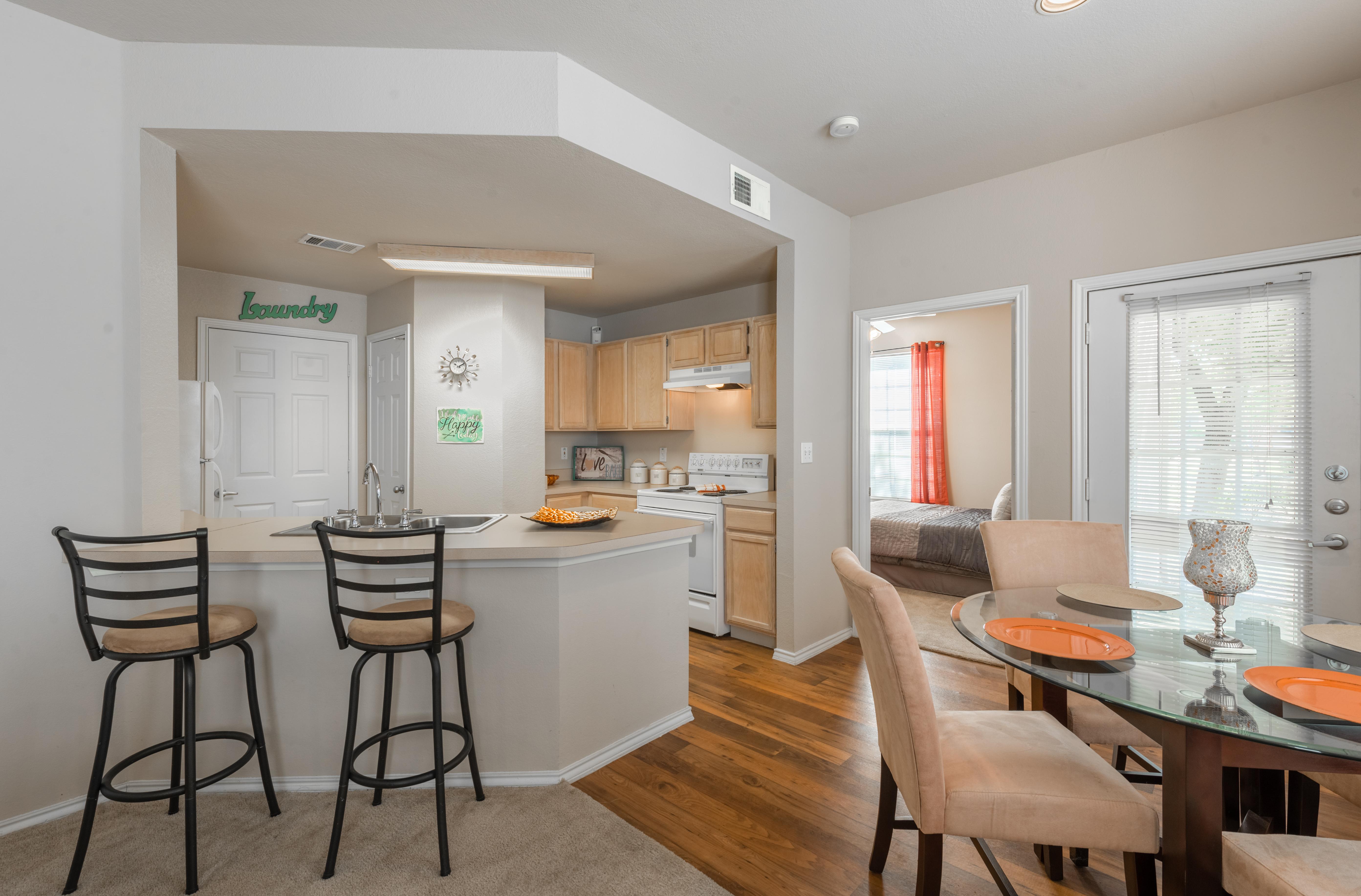 Kitchen peninsula with bar stools and dining area with table and chairs