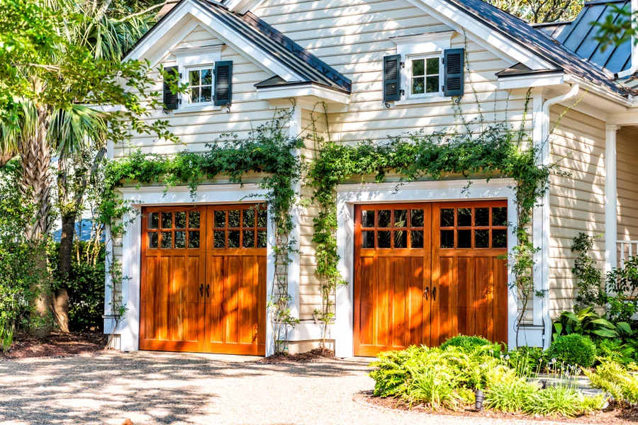 American residential house building in Charleston, South Carolina with two garage doors exterior with wooden architecture and ivy climbing plant