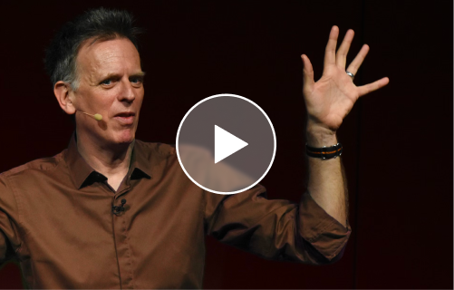 DAvid in brown shirt, talking to an audience