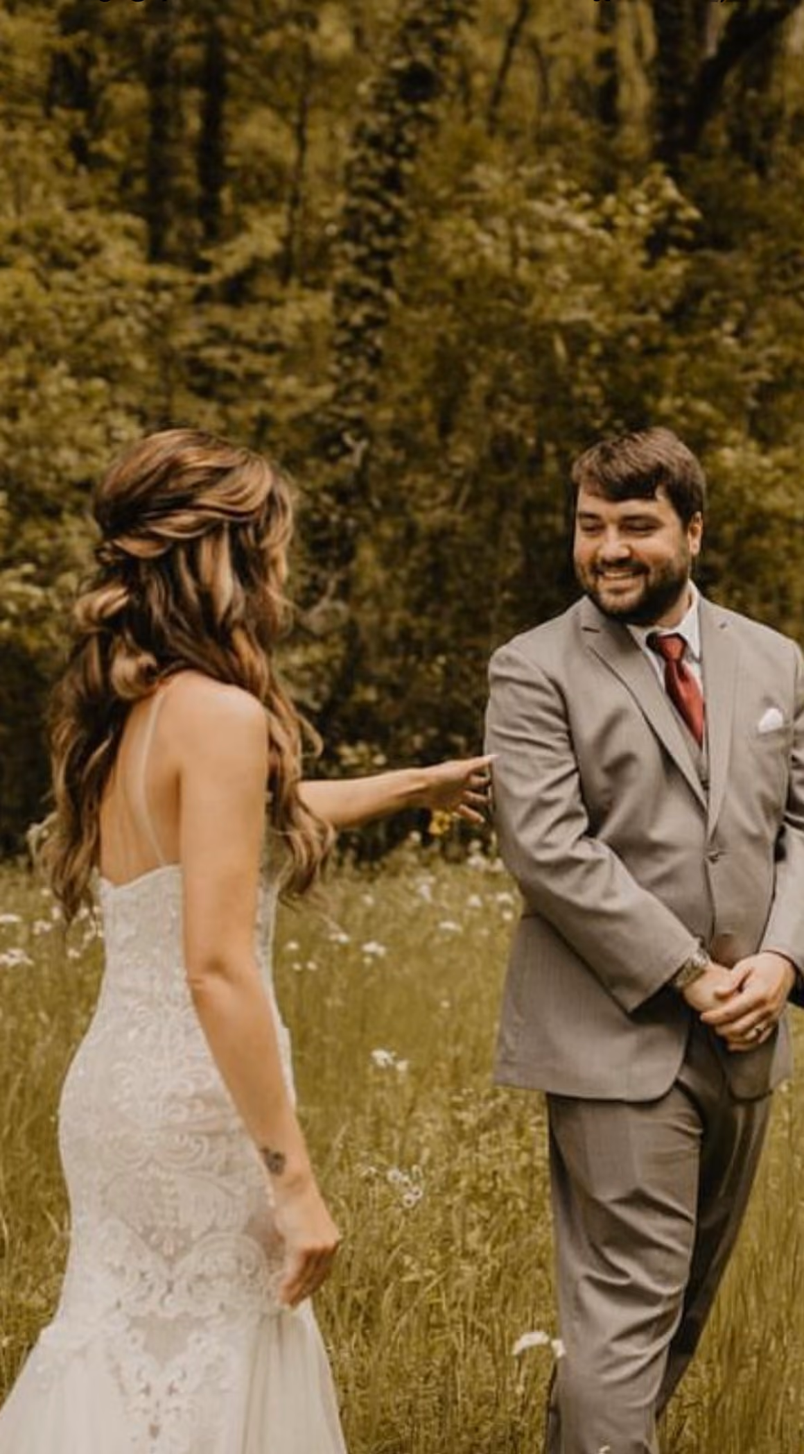 Bride and groom holding hands in a sunlit meadow