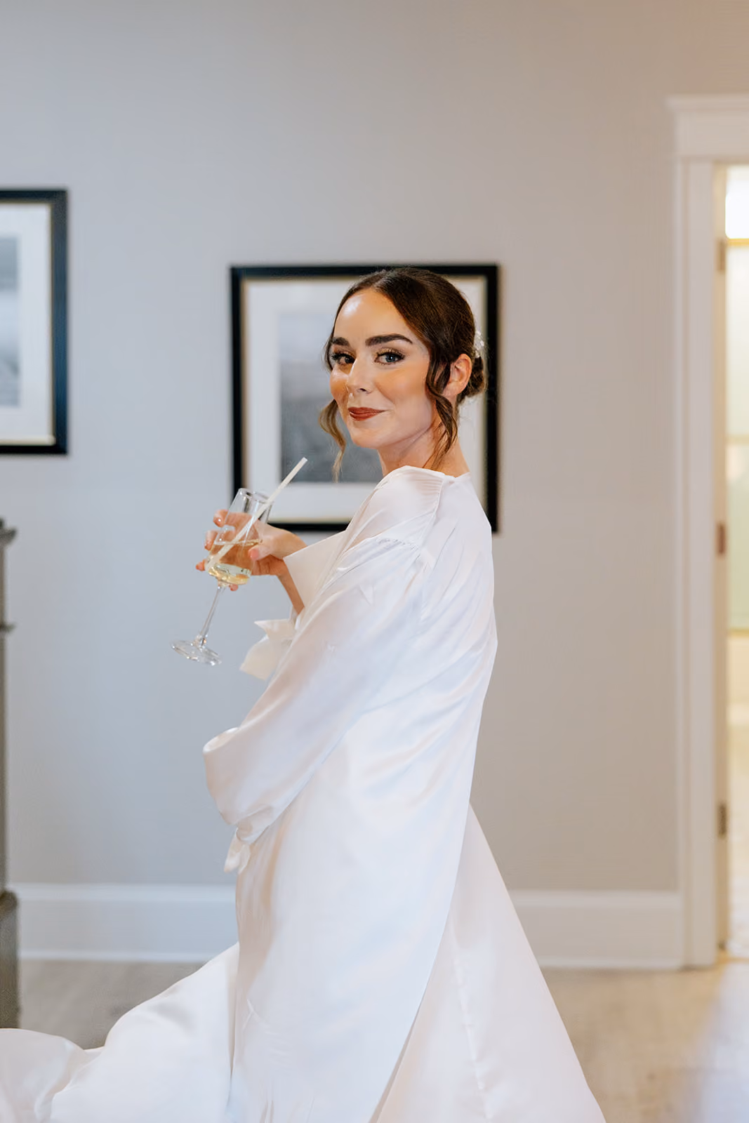 Bride holding a champagne glass with her gown train sweeping the floor