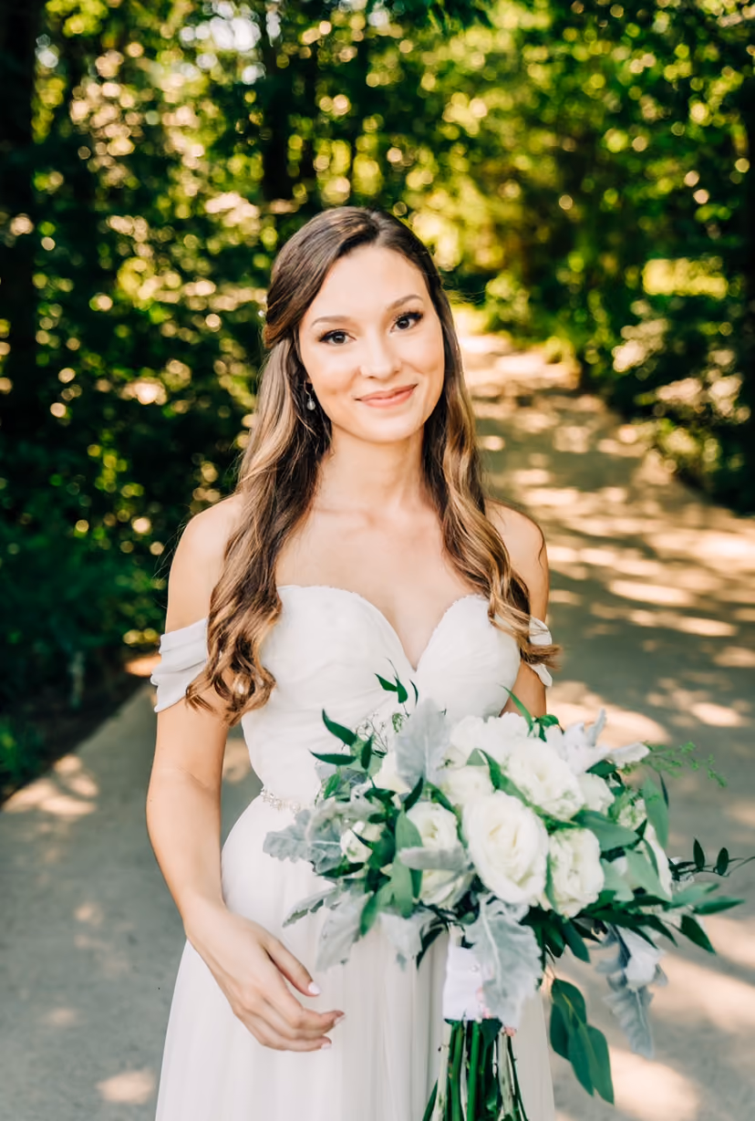 Bride with soft waves holding a white rose and eucalyptus bouquet