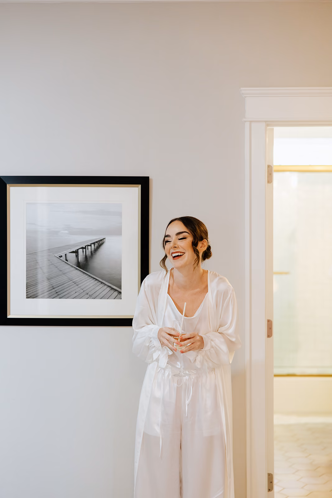 Bride laughing in a white robe in a bright getting-ready room