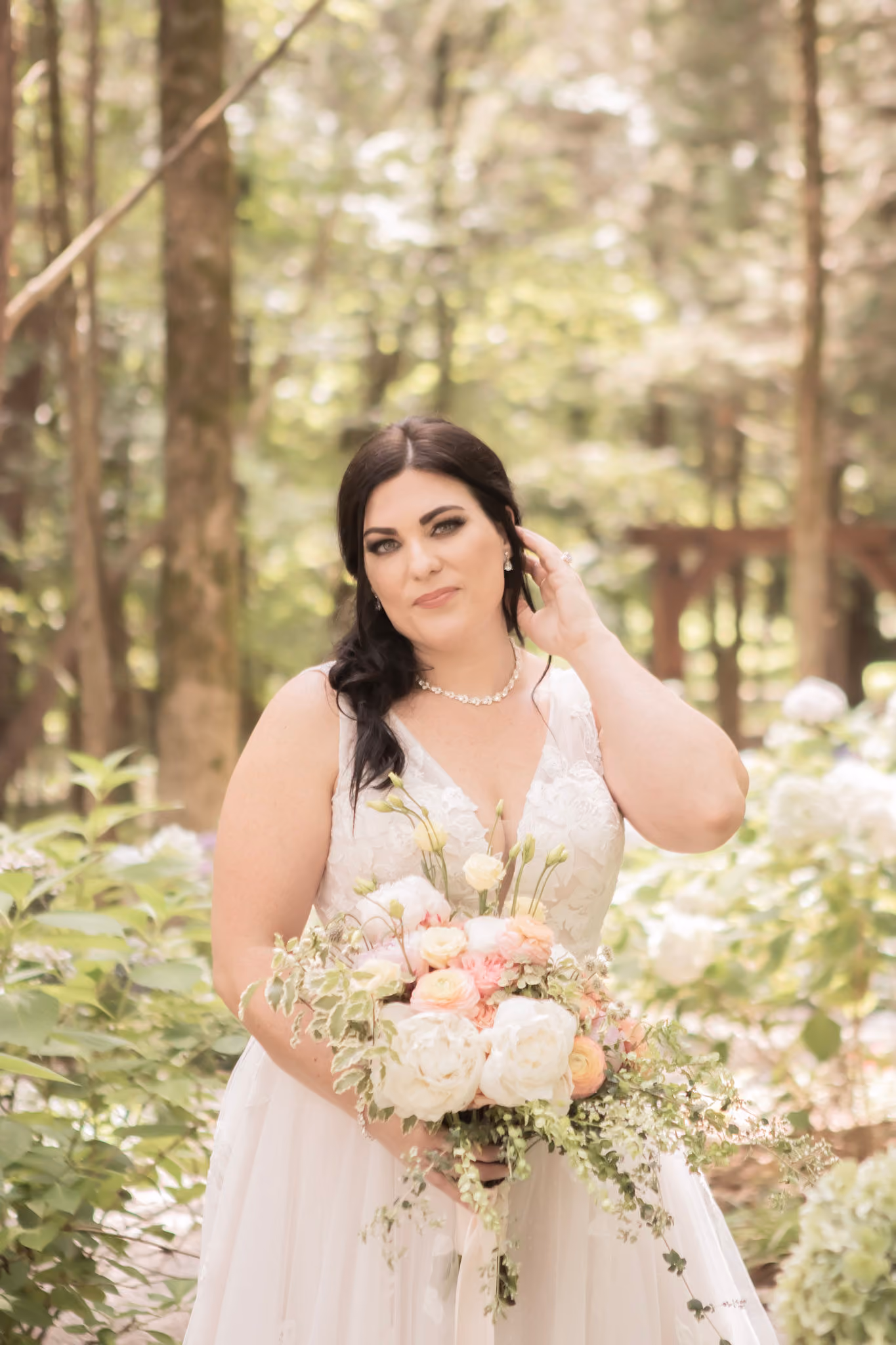 Bride holding a soft pink and cream bouquet among garden hydrangeas