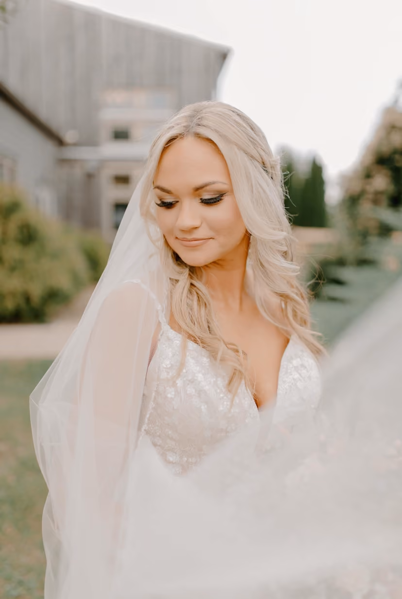 Bride with long blonde waves and a veil, looking down