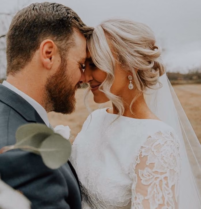Bride and groom forehead to forehead, her hair in a soft curled updo with a veil