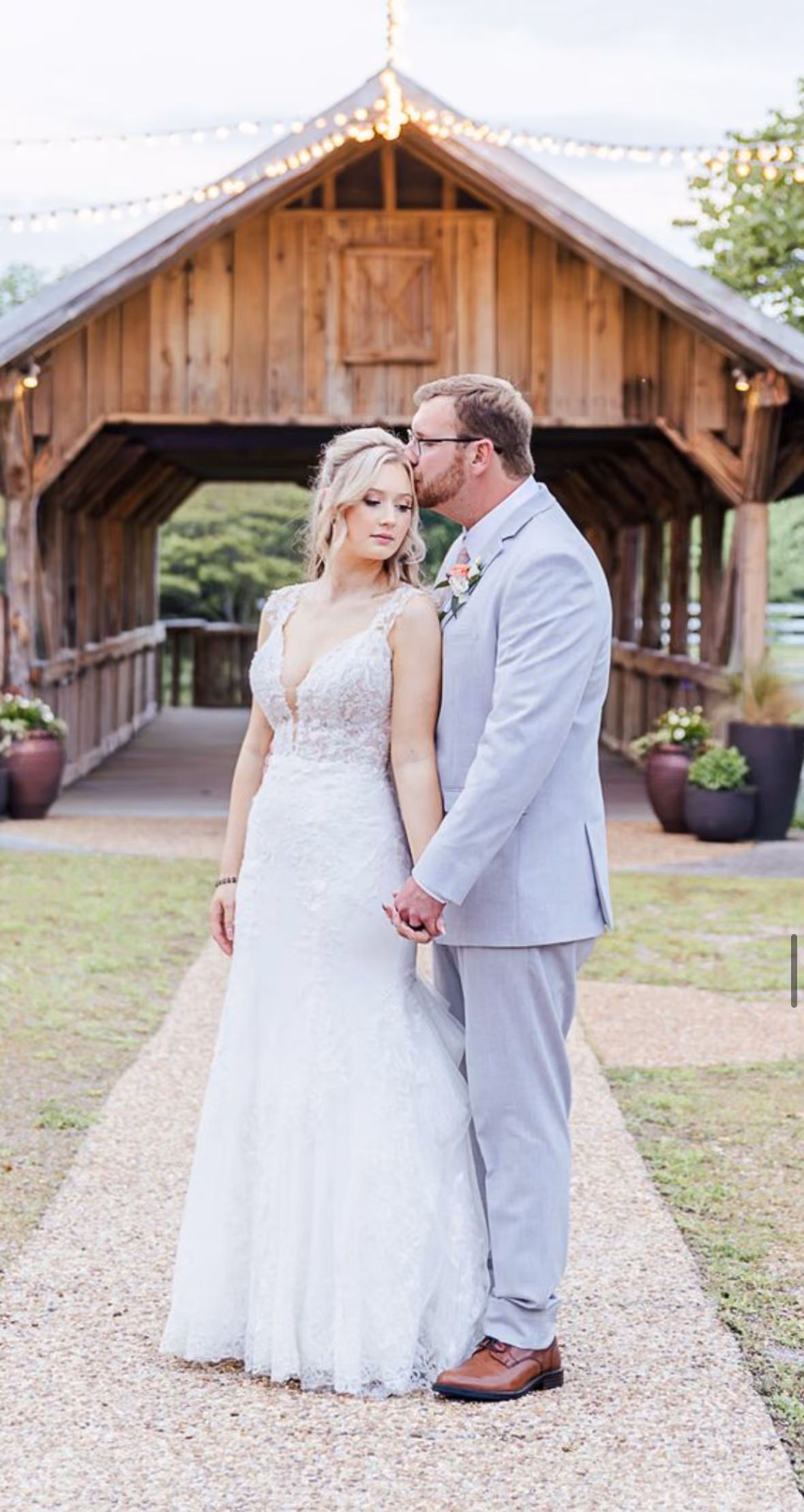 Bride and groom holding hands in front of a wooden barn venue