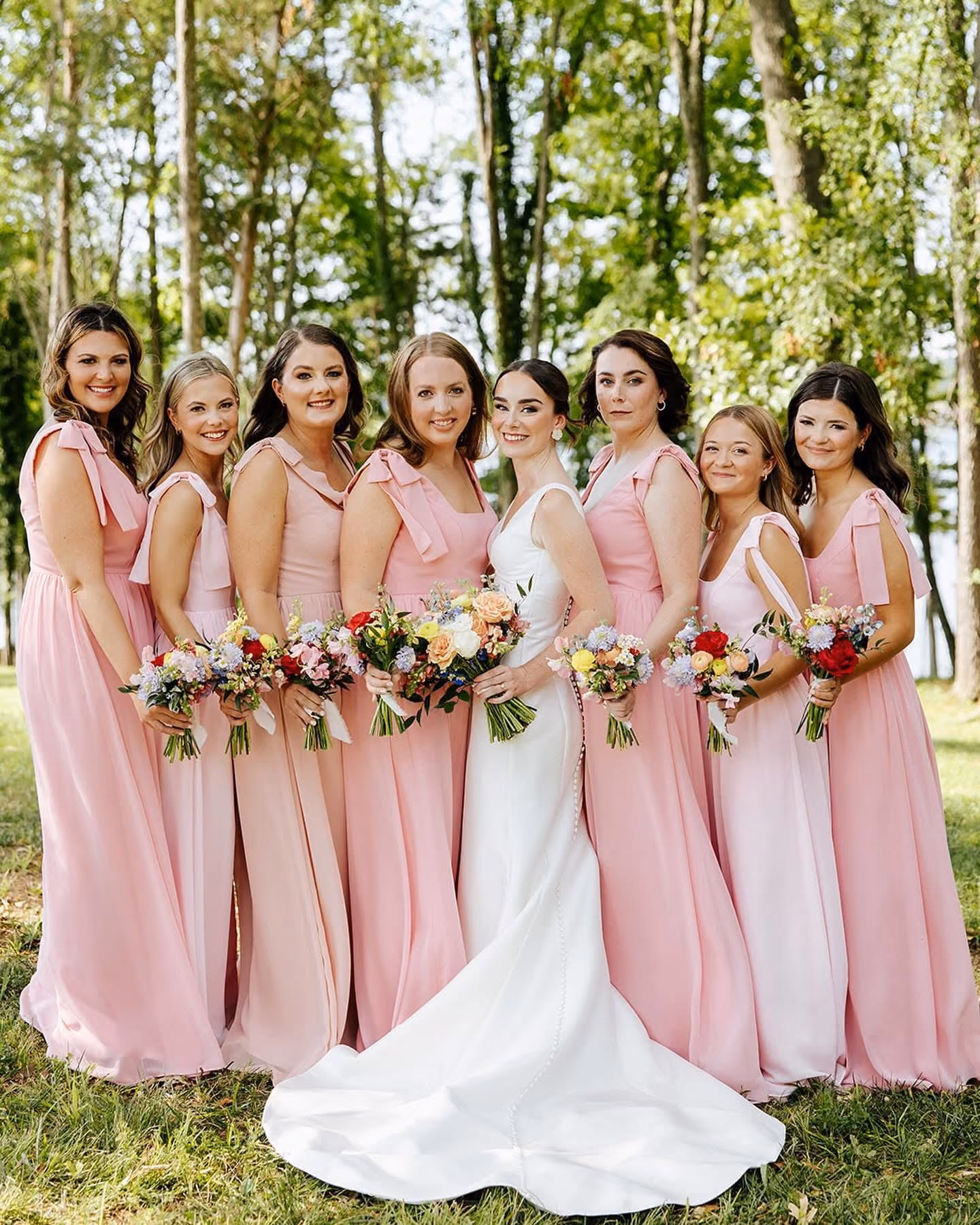 Bride with her bridesmaids in blush gowns holding colourful bouquets