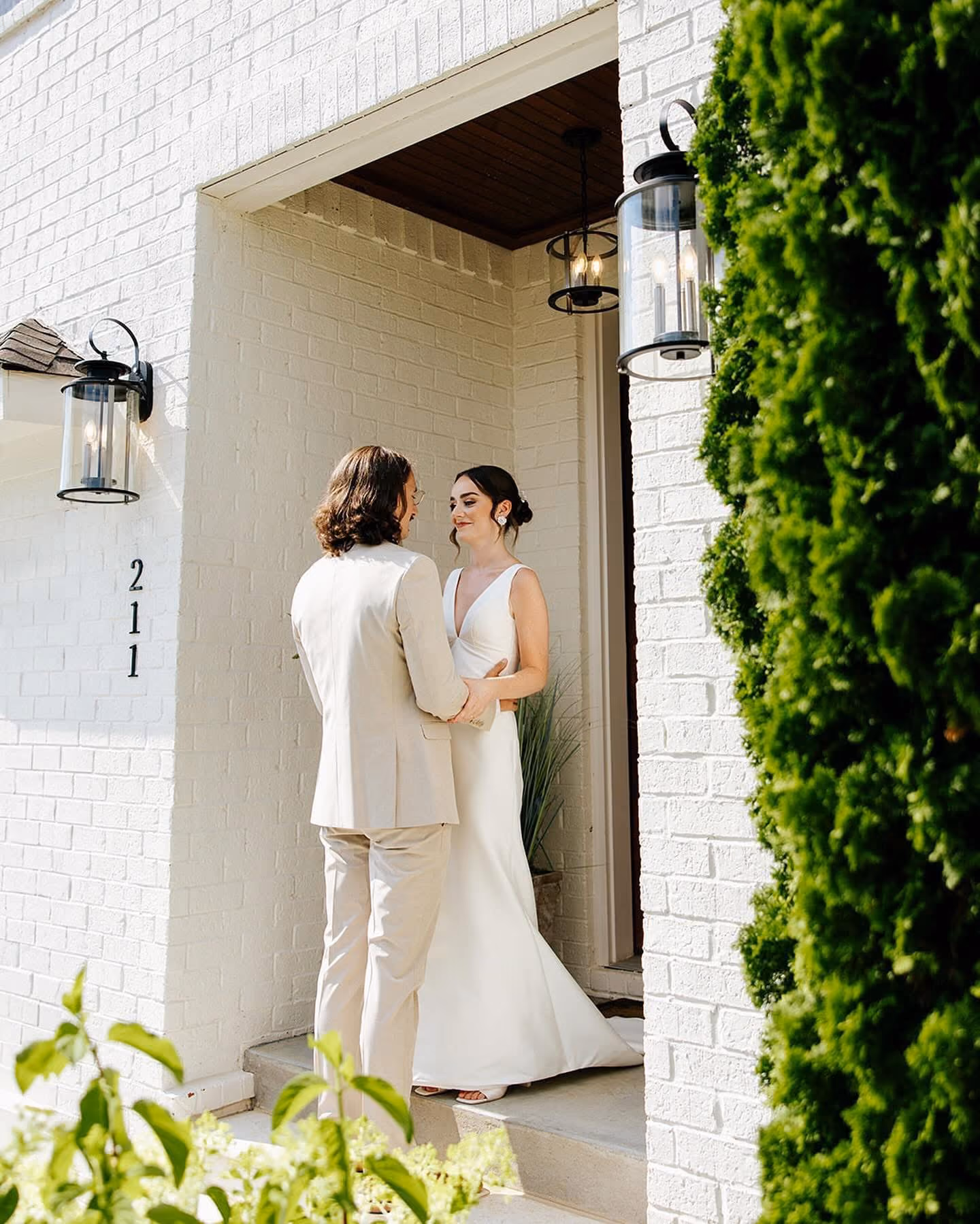 Bride and groom sharing a first look in a white brick doorway