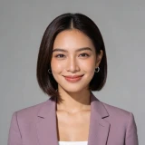 Smiling woman with straight black hair wearing a mauve blazer and hoop earrings against a gray background.