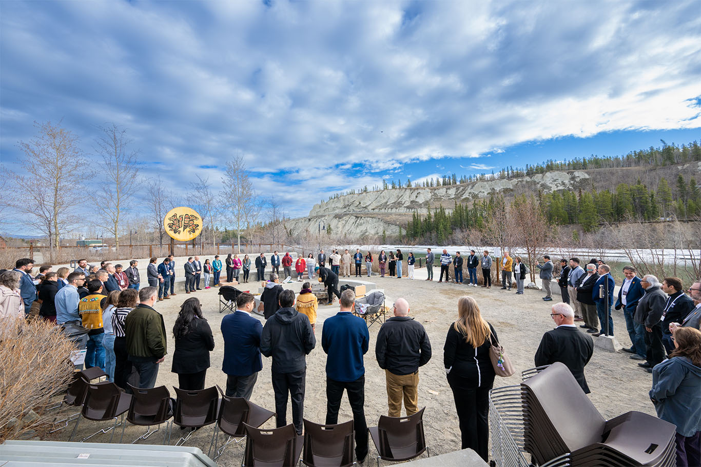 Participants gathered in a large outdoor circle beside a river.