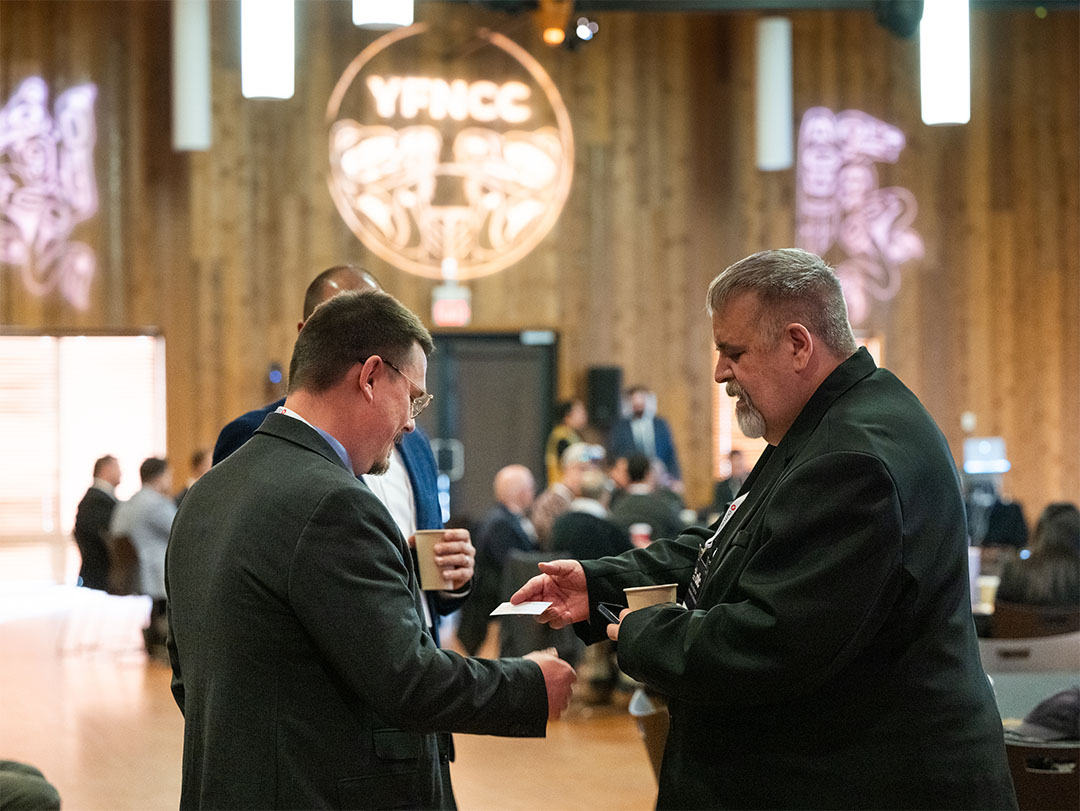 Attendees exchanging business cards at a YFNCC gathering.